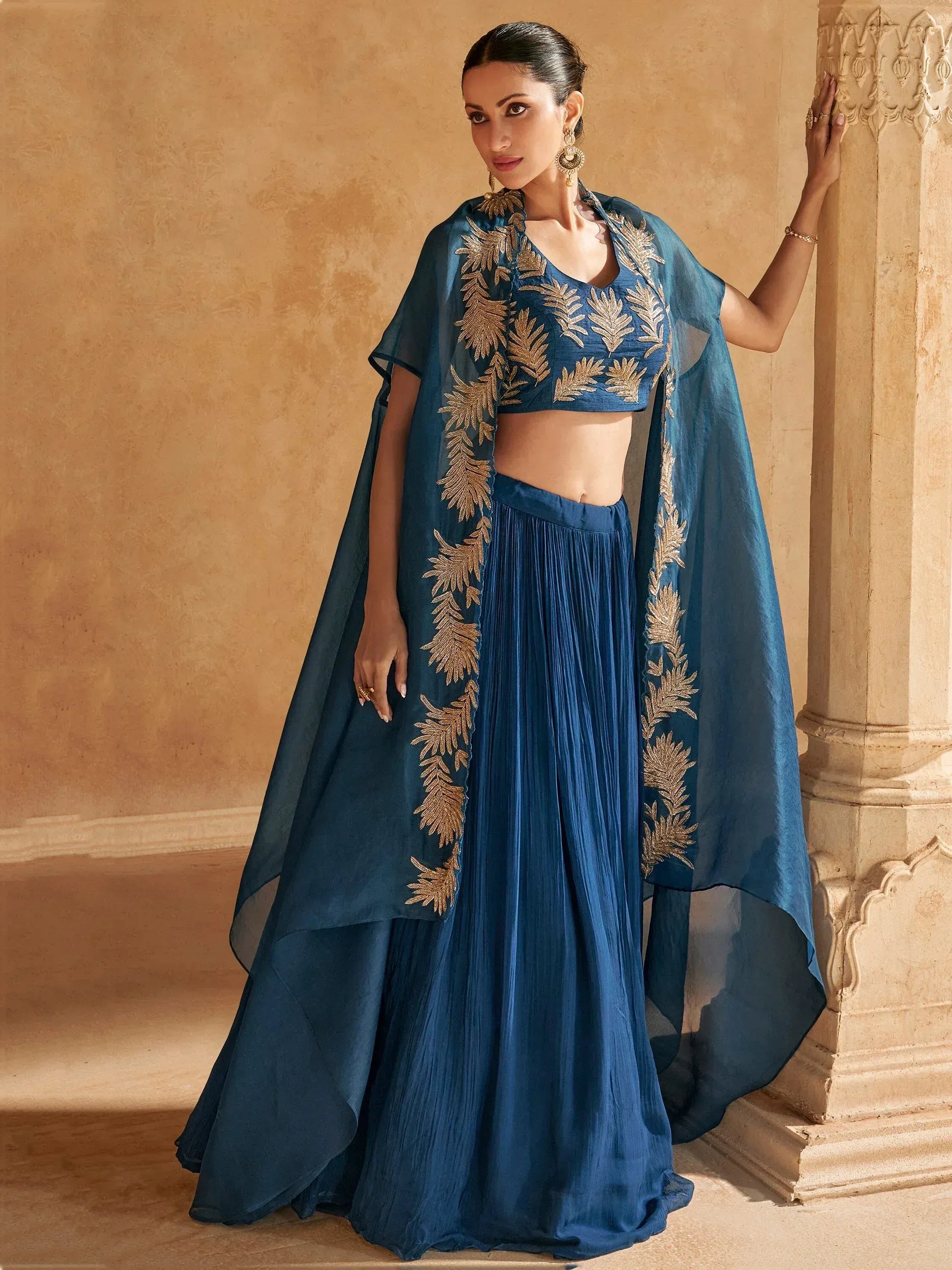 Blue embroidered lehenga choli with gold leaf detailing, sheer cape, and pleated skirt for Indian ethnic wear