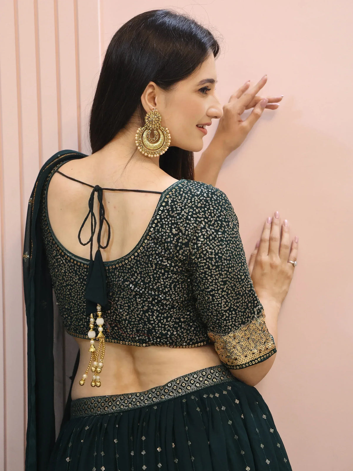 Woman in green sequin lehenga choli with back tie blouse and gold jhumka earrings
