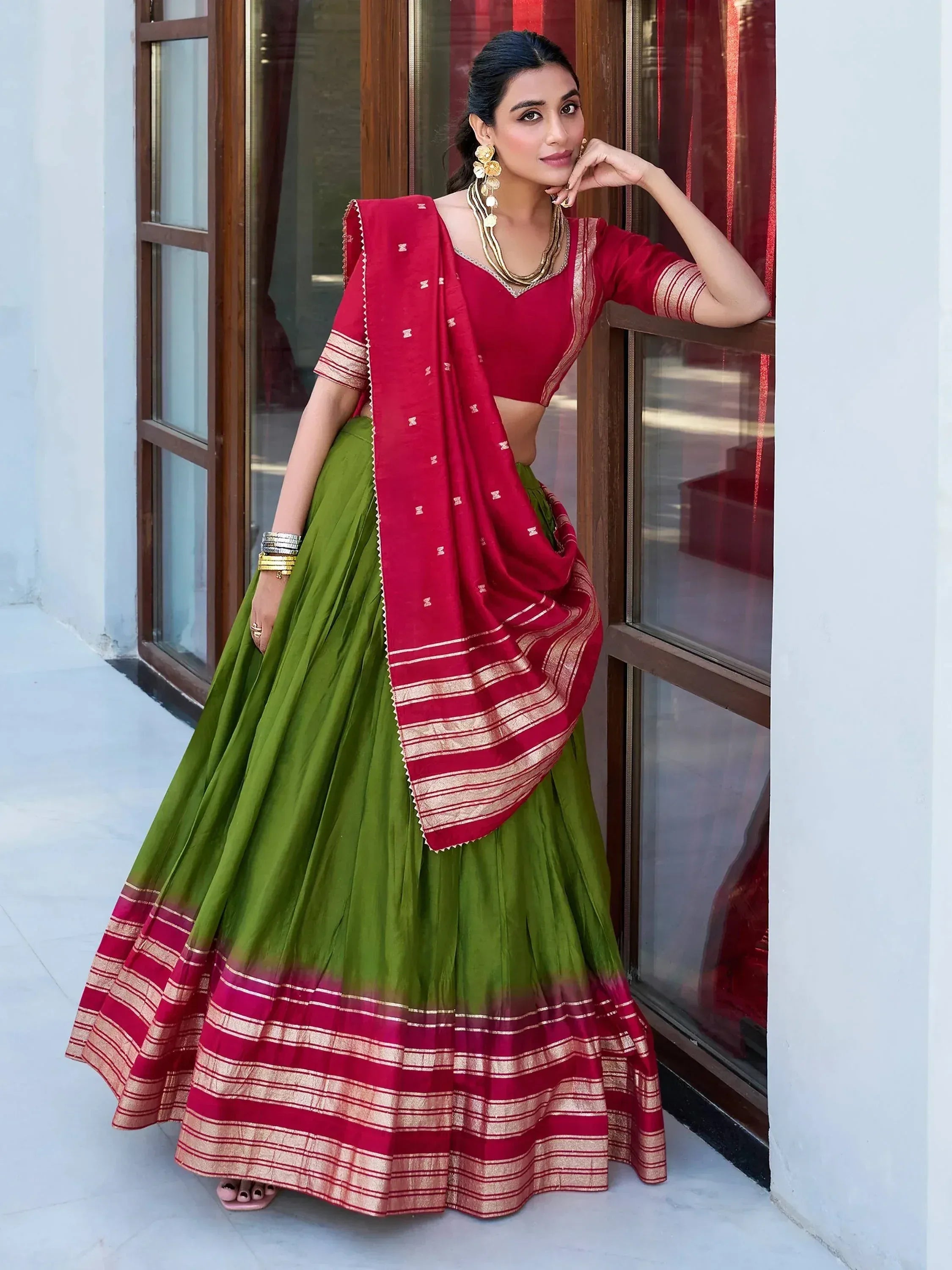 Green and red ethnic lehenga choli with gold trim, perfect for Indian weddings and festivals