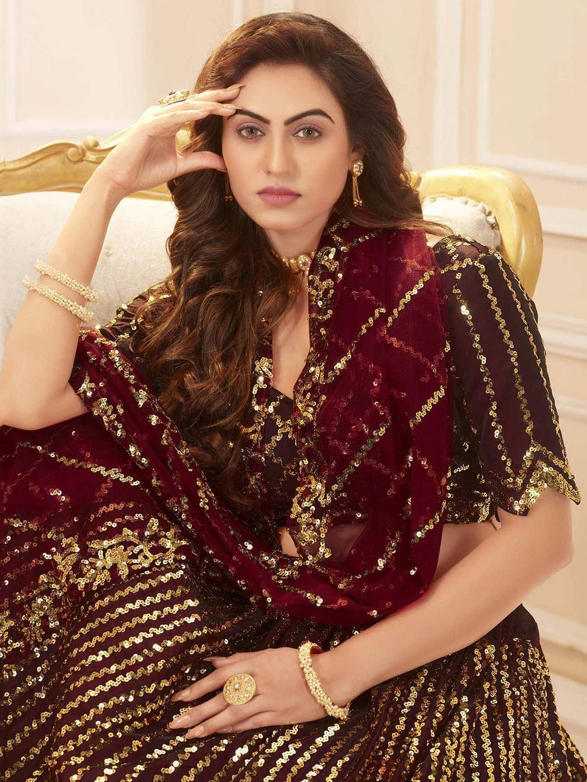 Elegant maroon and gold sequin lehenga choli with sheer sleeves, perfect for Indian ethnic wear occasions.