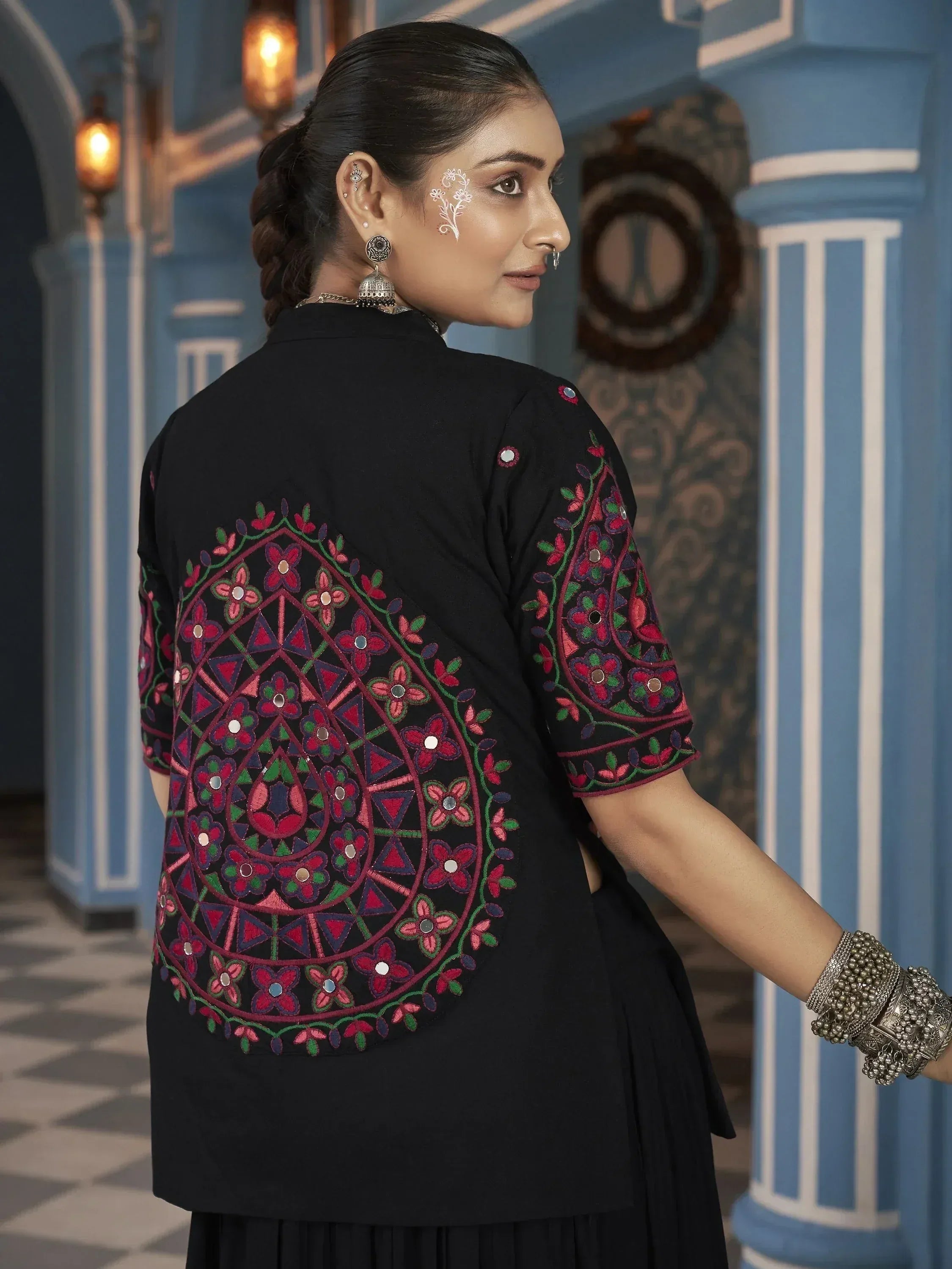 Black ethnic kurta with vibrant floral embroidery and mirror work, paired with traditional jewelry