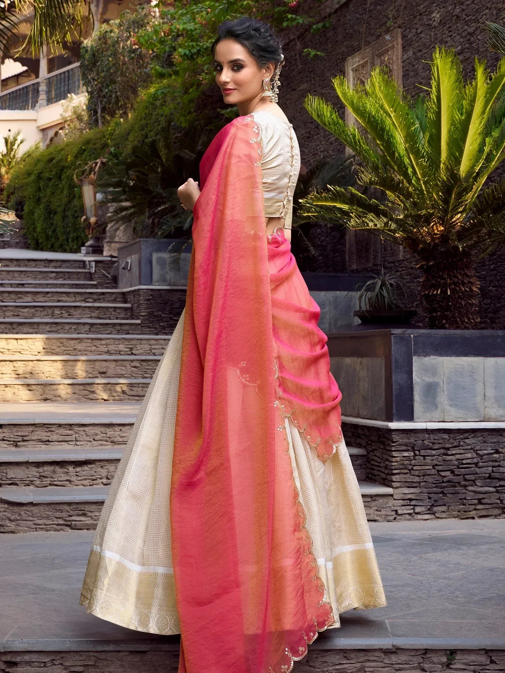 Woman in pink and cream designer saree with gold embroidery, styled for ethnic occasions