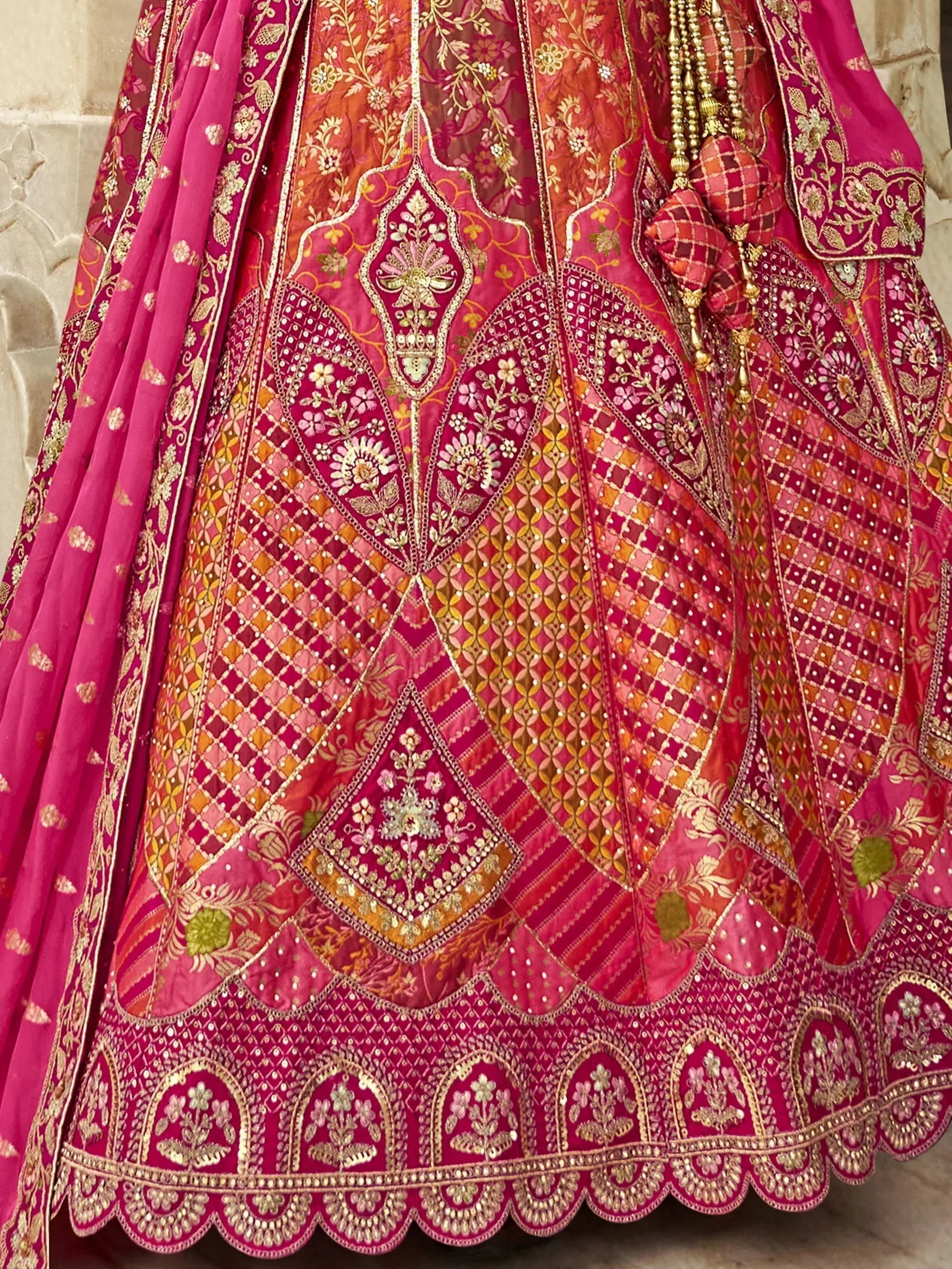 Pink and gold embroidered lehenga choli with intricate floral patterns and mirror work, perfect for Indian weddings.