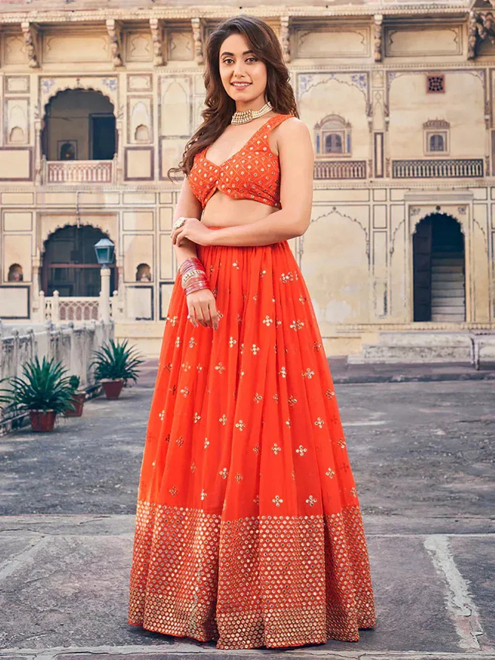Vibrant orange lehenga choli with mirror work, perfect for Indian ethnic wear and festive occasions.