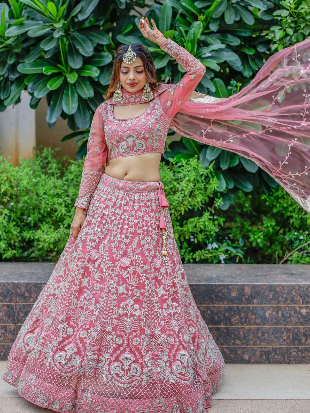 Pink embroidered lehenga choli with floral motifs, sheer dupatta, and traditional jewelry for Indian ethnic wear