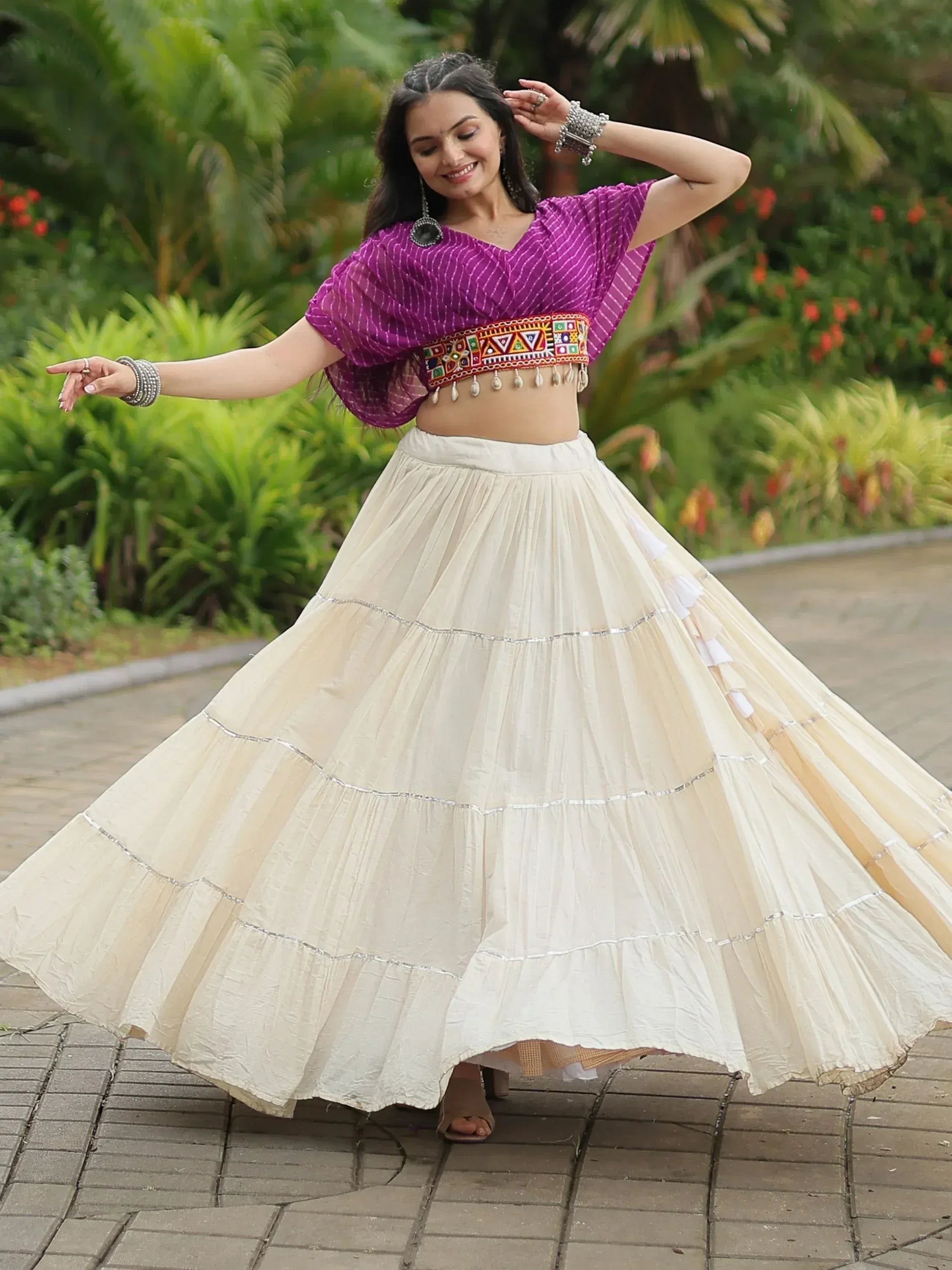 Woman in purple ethnic crop top and cream tiered skirt, dancing outdoors