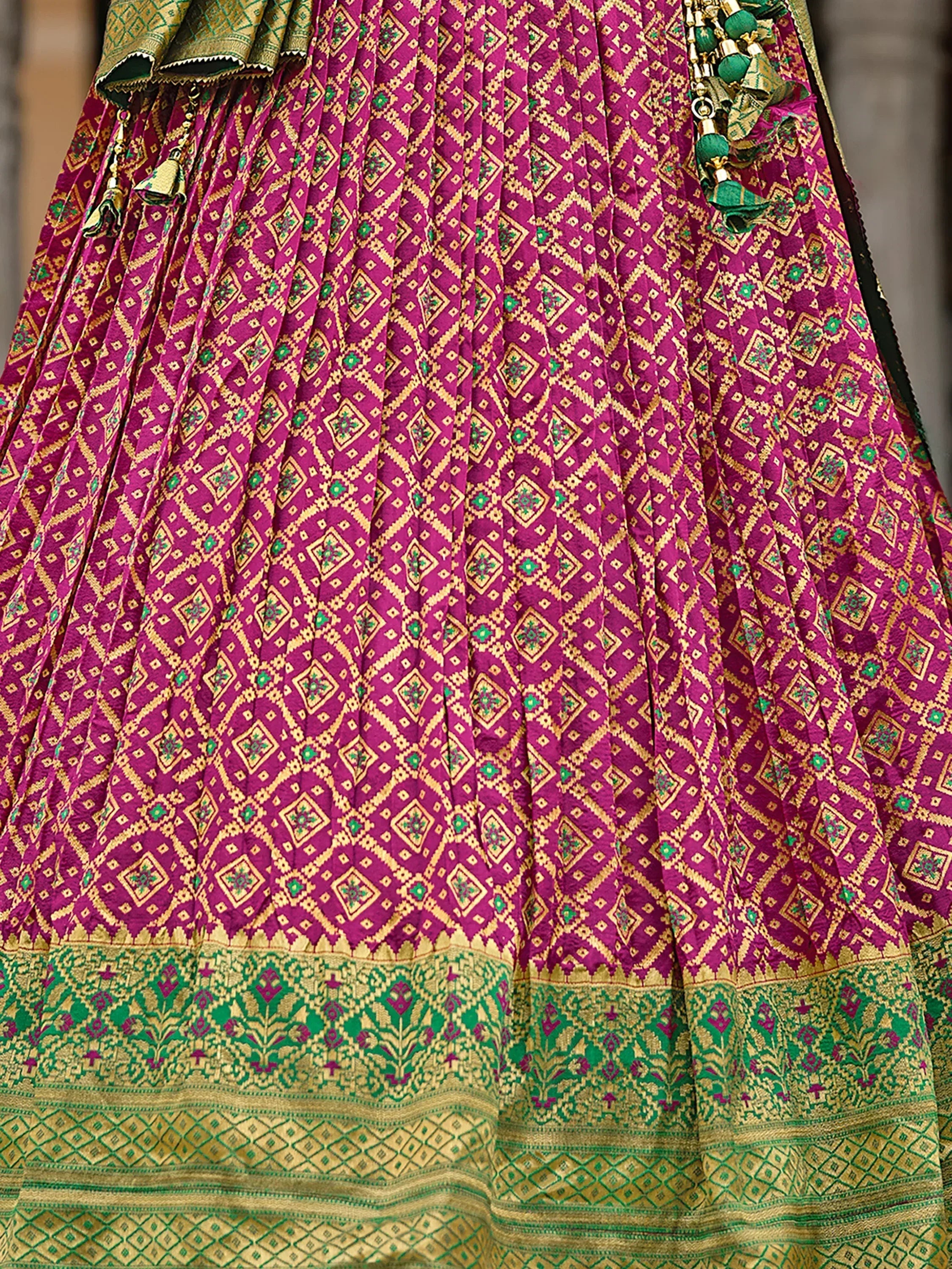 Purple and green ethnic lehenga with gold geometric patterns and tassels, perfect for Indian weddings or festivals.