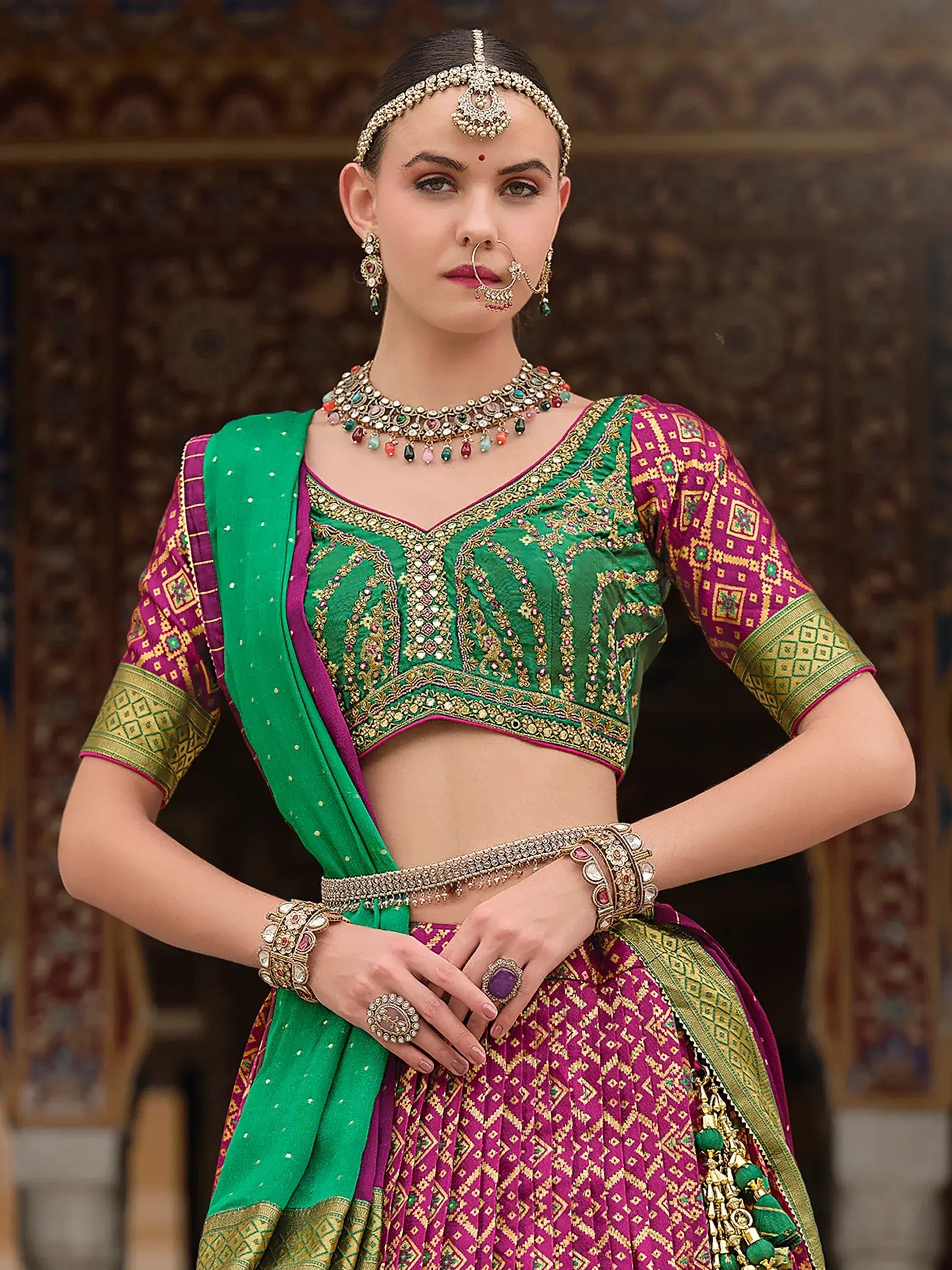 Green and magenta embroidered lehenga choli with traditional Indian jewelry for festive occasions