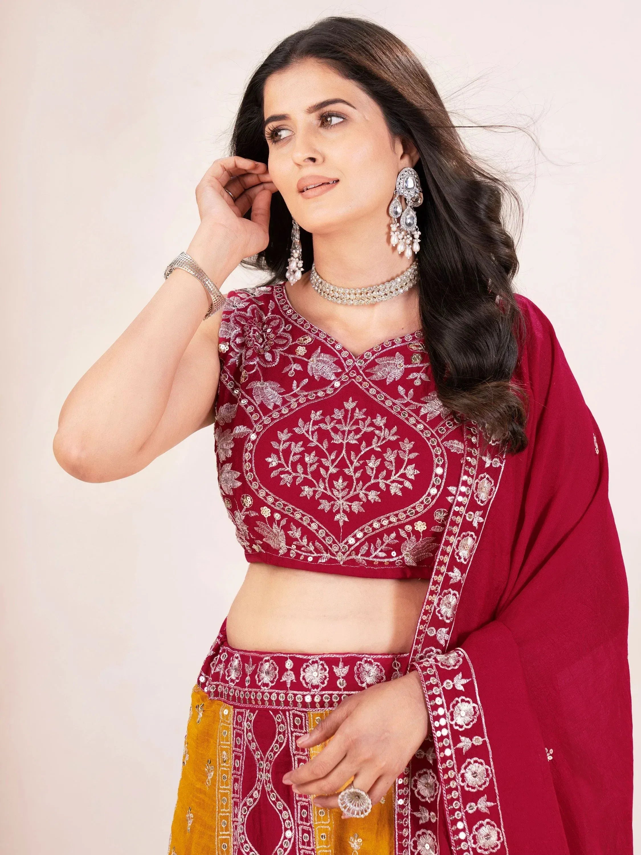 Maroon embroidered lehenga choli with gold detailing, paired with statement jewelry for Indian ethnic wear