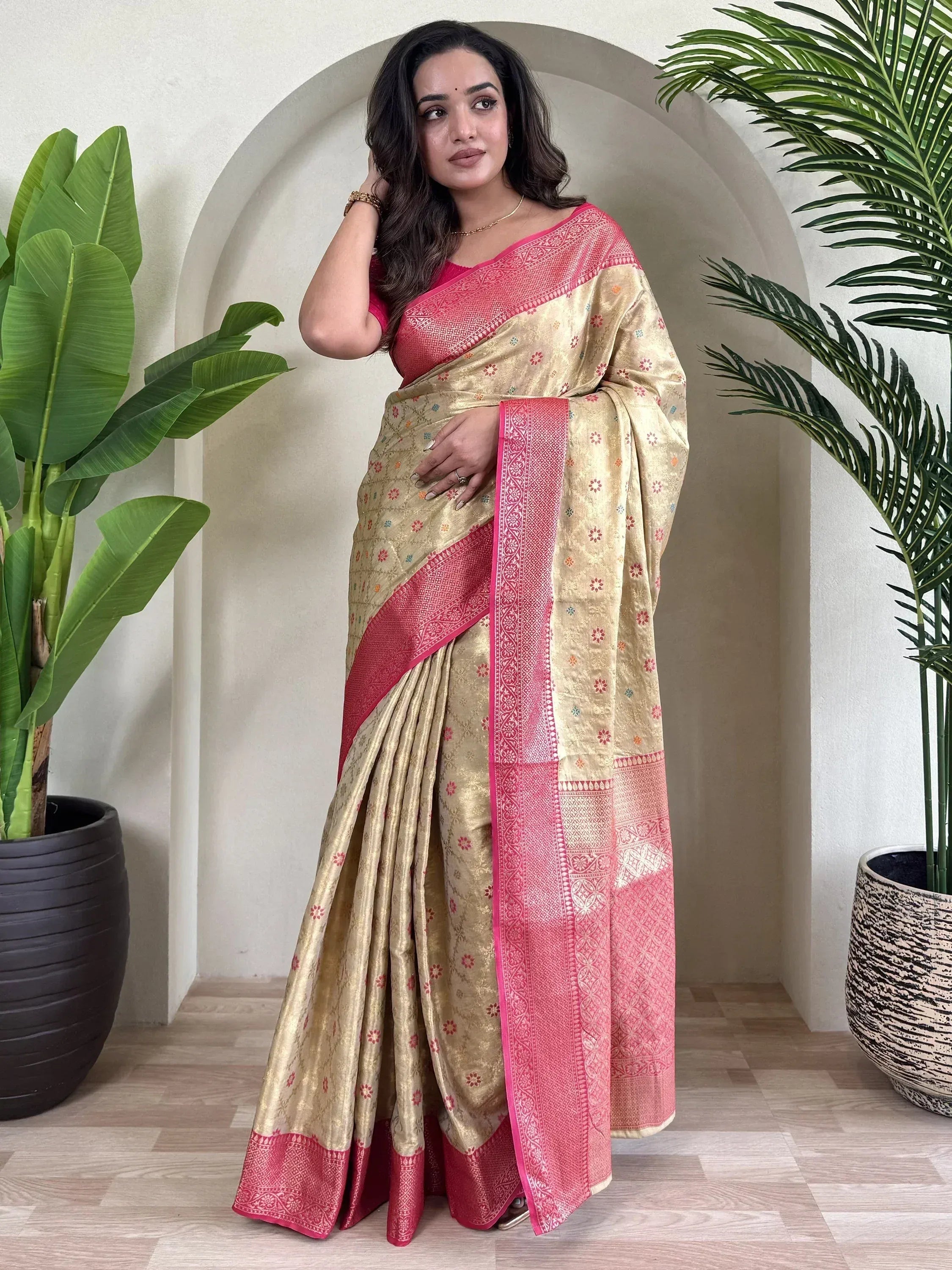 Woman in gold and pink ethnic saree with floral motifs, perfect for Indian occasions and festive wear.