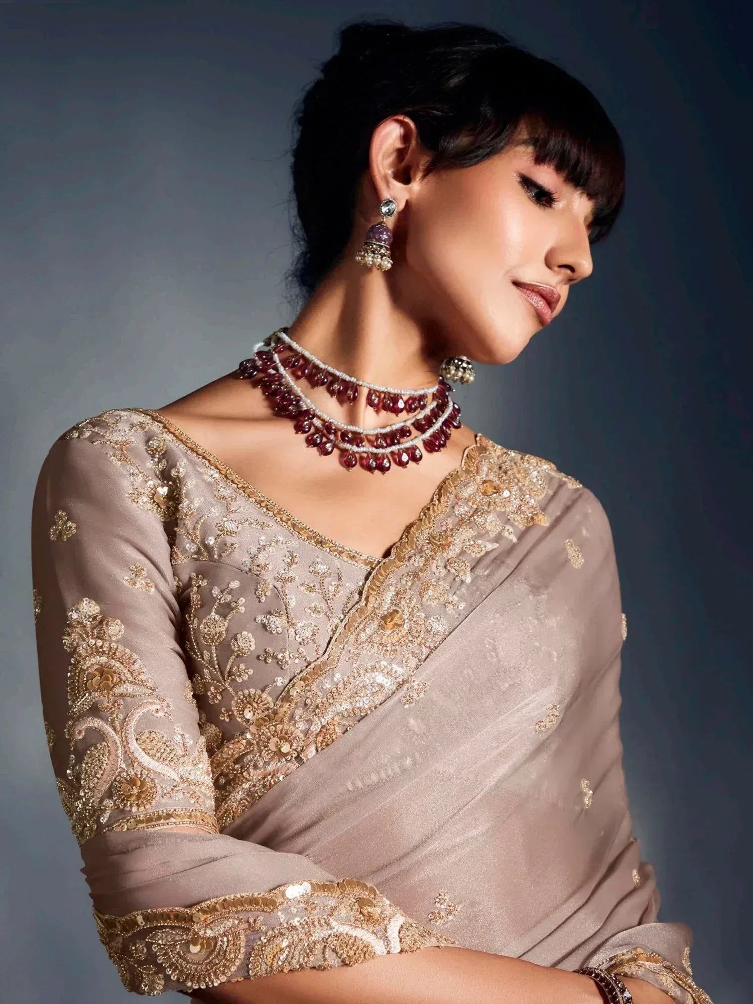 Elegant woman in embroidered ethnic saree with gold detailing and statement jewelry