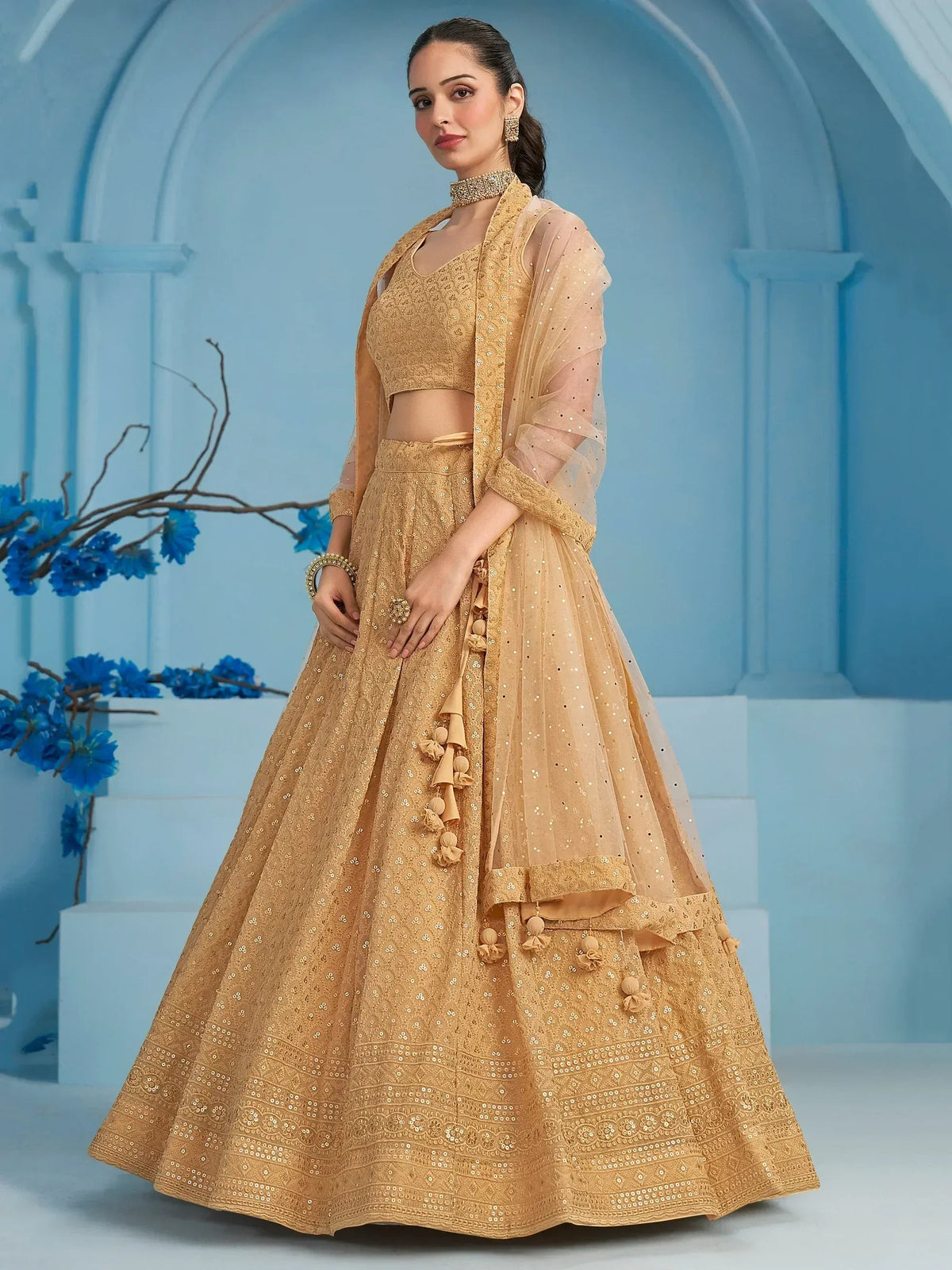 Elegant gold lehenga choli with sequin embroidery and tassels, perfect for Indian weddings and festive occasions.