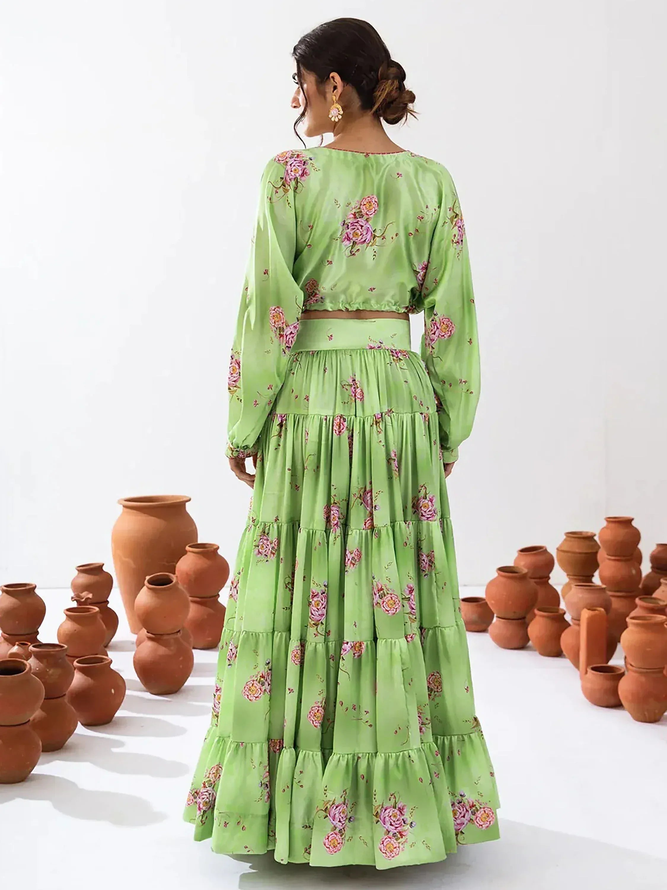 Green floral ethnic gown with tiered skirt and long sleeves, styled with clay pots