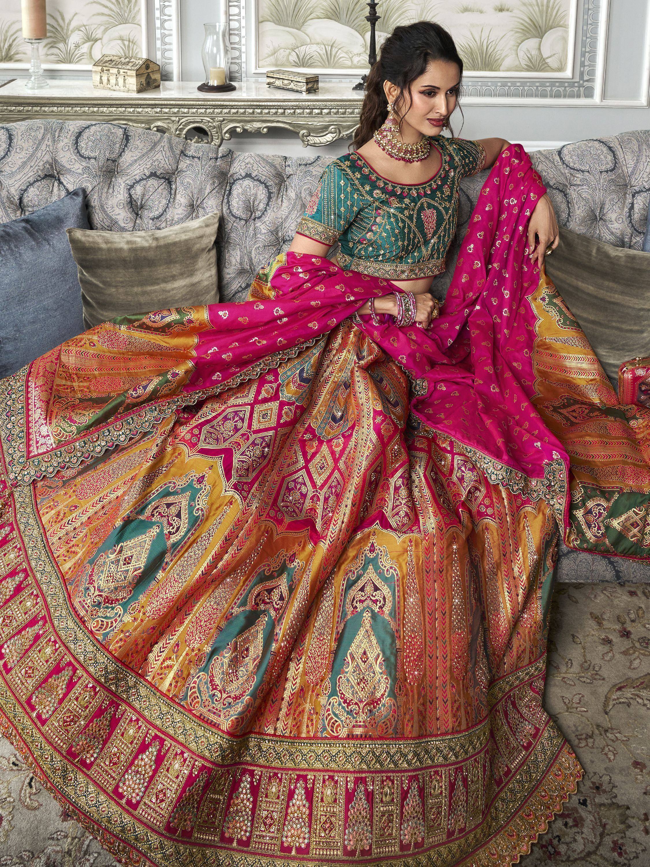 Woman in vibrant pink and green designer lehenga choli with intricate gold embroidery, perfect for Indian weddings.