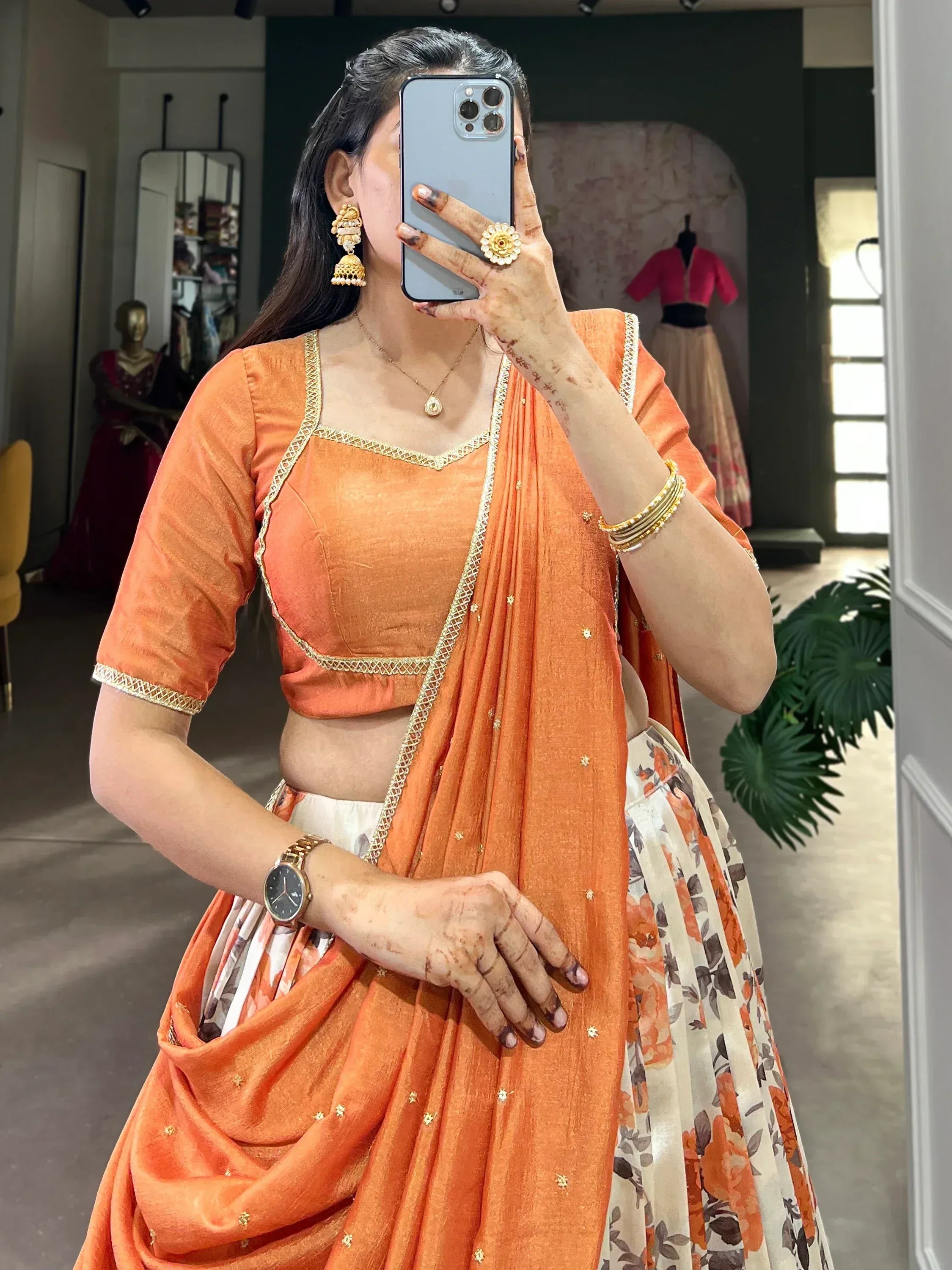 Orange designer lehenga choli with gold embroidery, floral skirt, and traditional jewelry for Indian ethnic wear