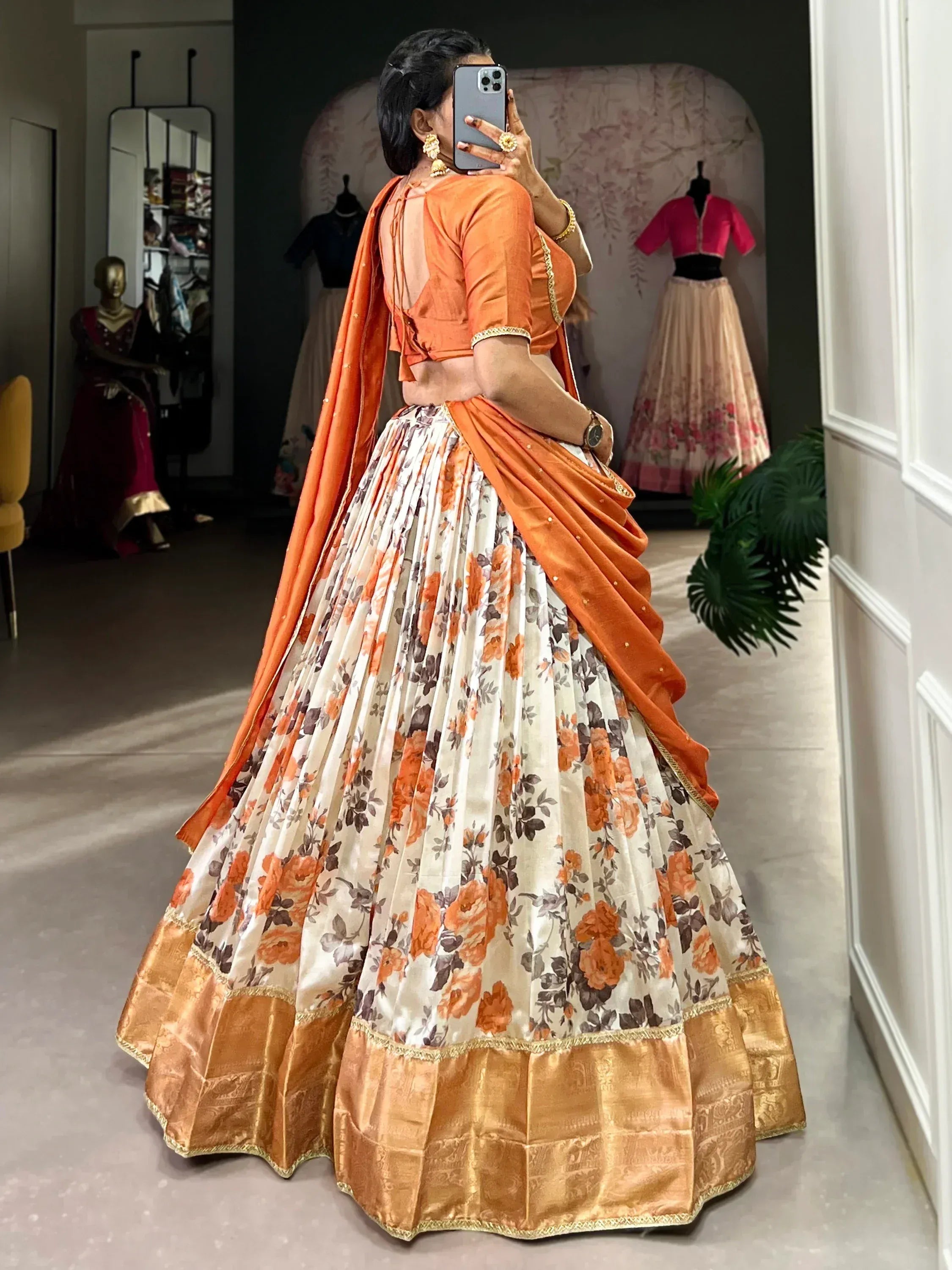 Orange floral lehenga choli with gold border, back view in boutique