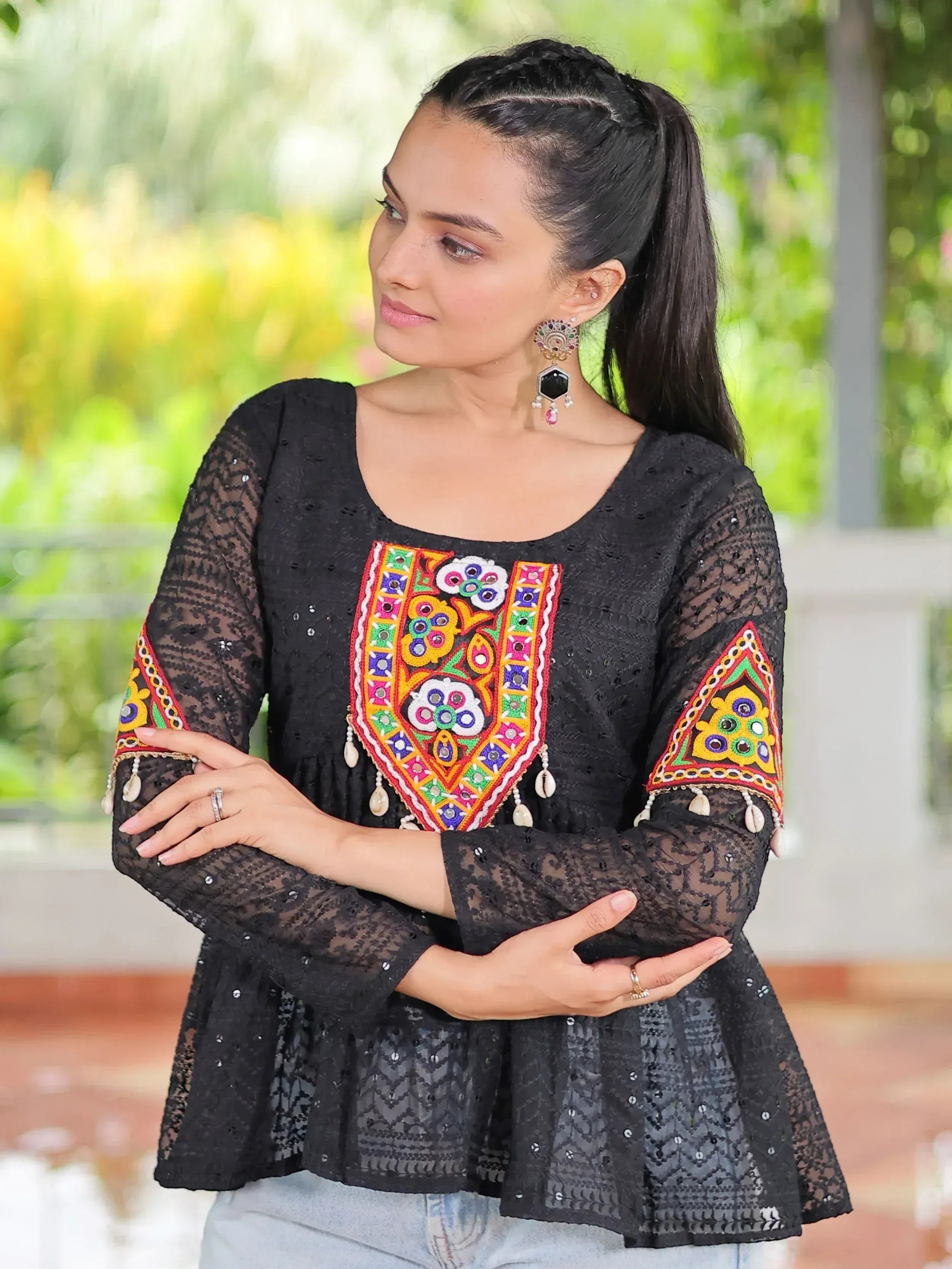 Black embroidered ethnic top with colorful mirror work and lace sleeves, paired with jeans for a fusion look.