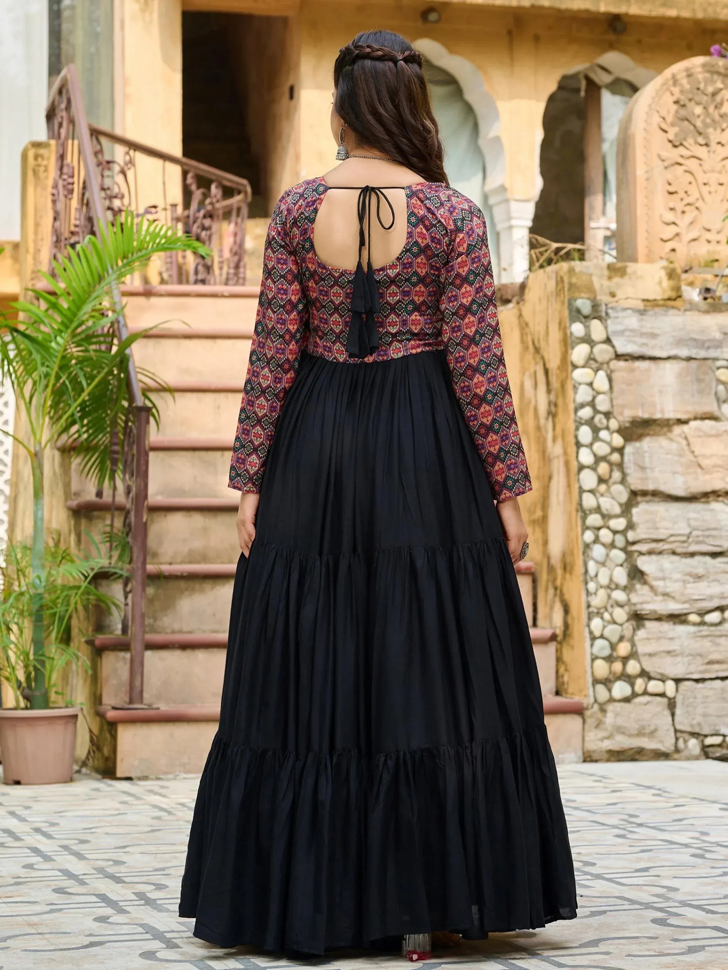 Woman in ethnic printed top and black tiered skirt, back view, traditional Indian wear
