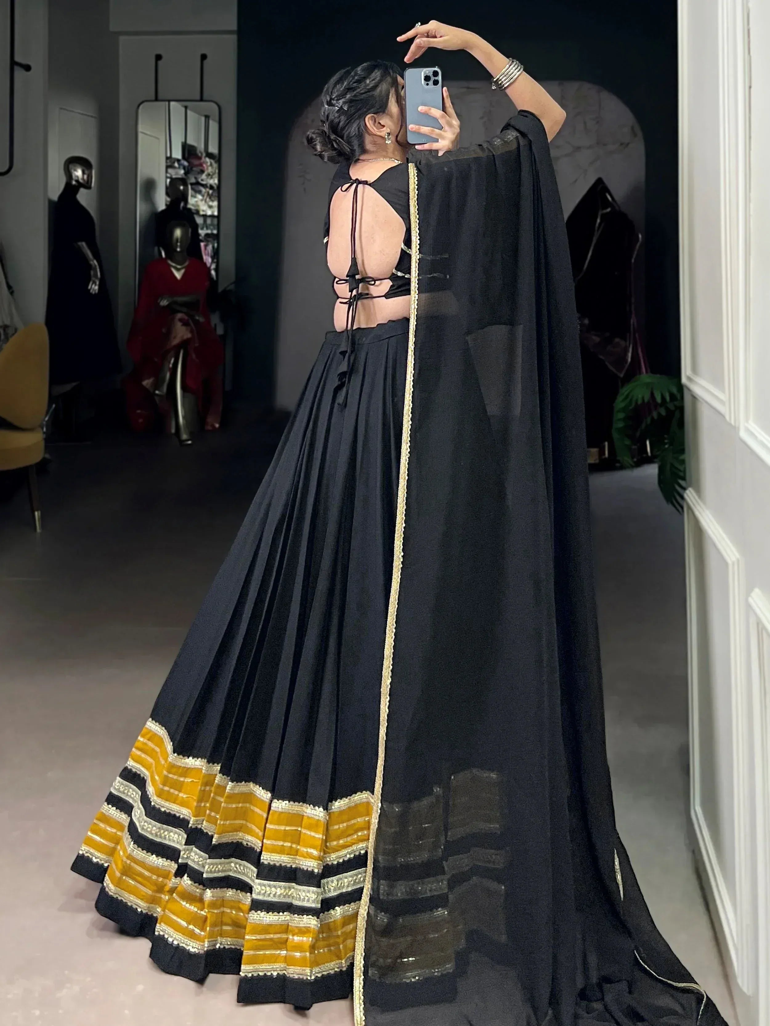 Black lehenga choli with gold border, backless blouse, and sheer dupatta for ethnic wear