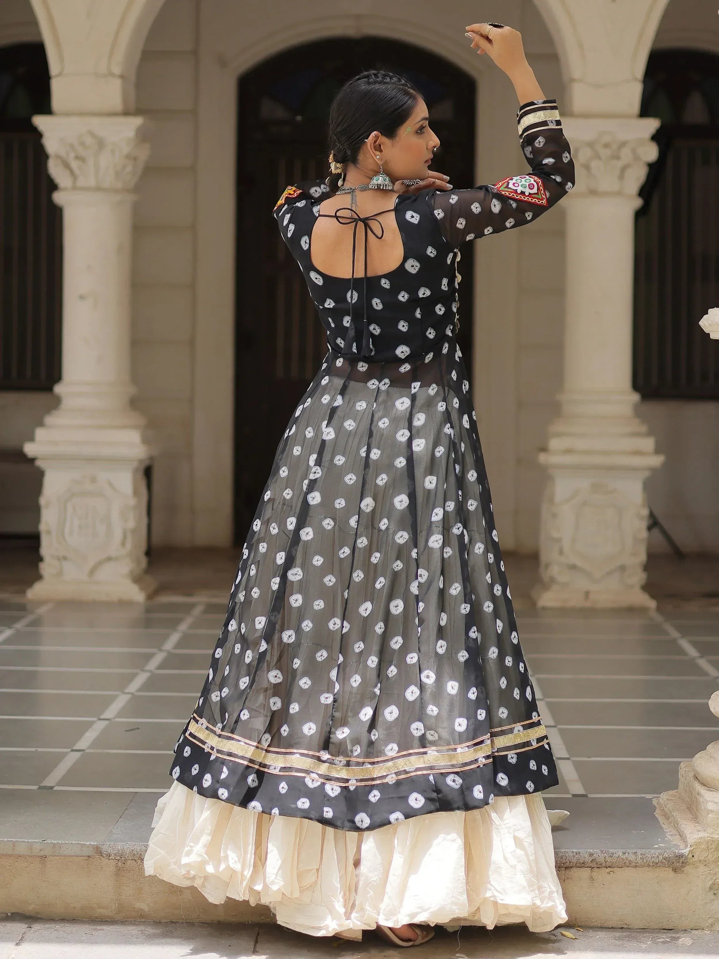 Black and grey printed ethnic gown with sheer overlay, gold trim, and back tie detail, styled with traditional jewelry.