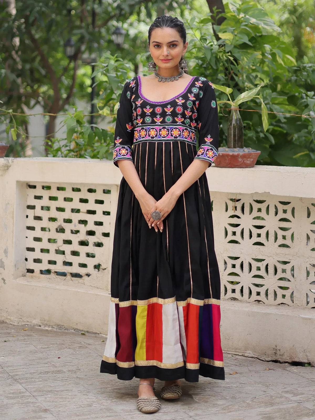 Black embroidered ethnic gown with colorful floral patterns and striped hem, perfect for Indian wear