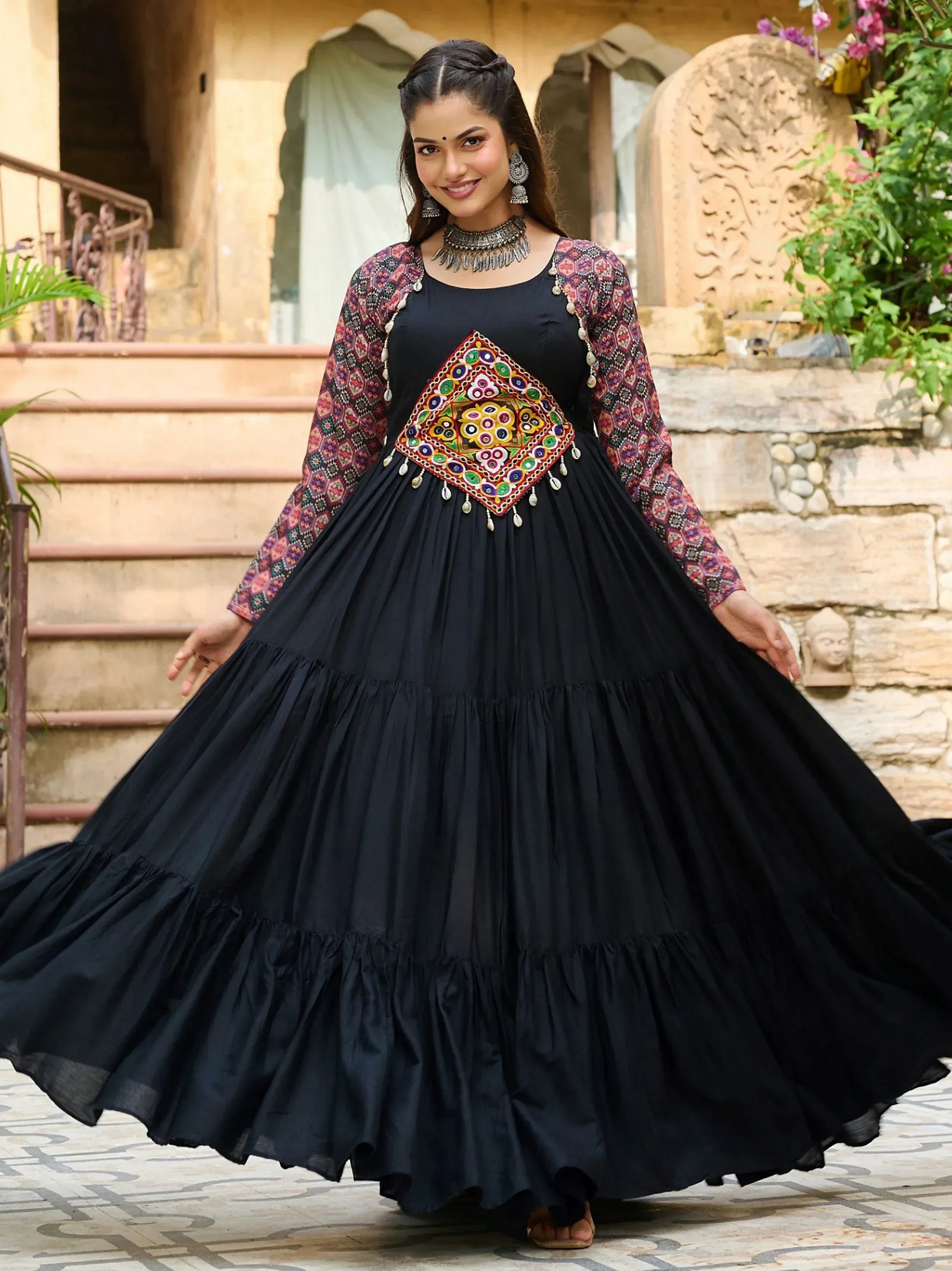 Black ethnic gown with colorful mirror work and tiered skirt, perfect for Indian festive occasions.