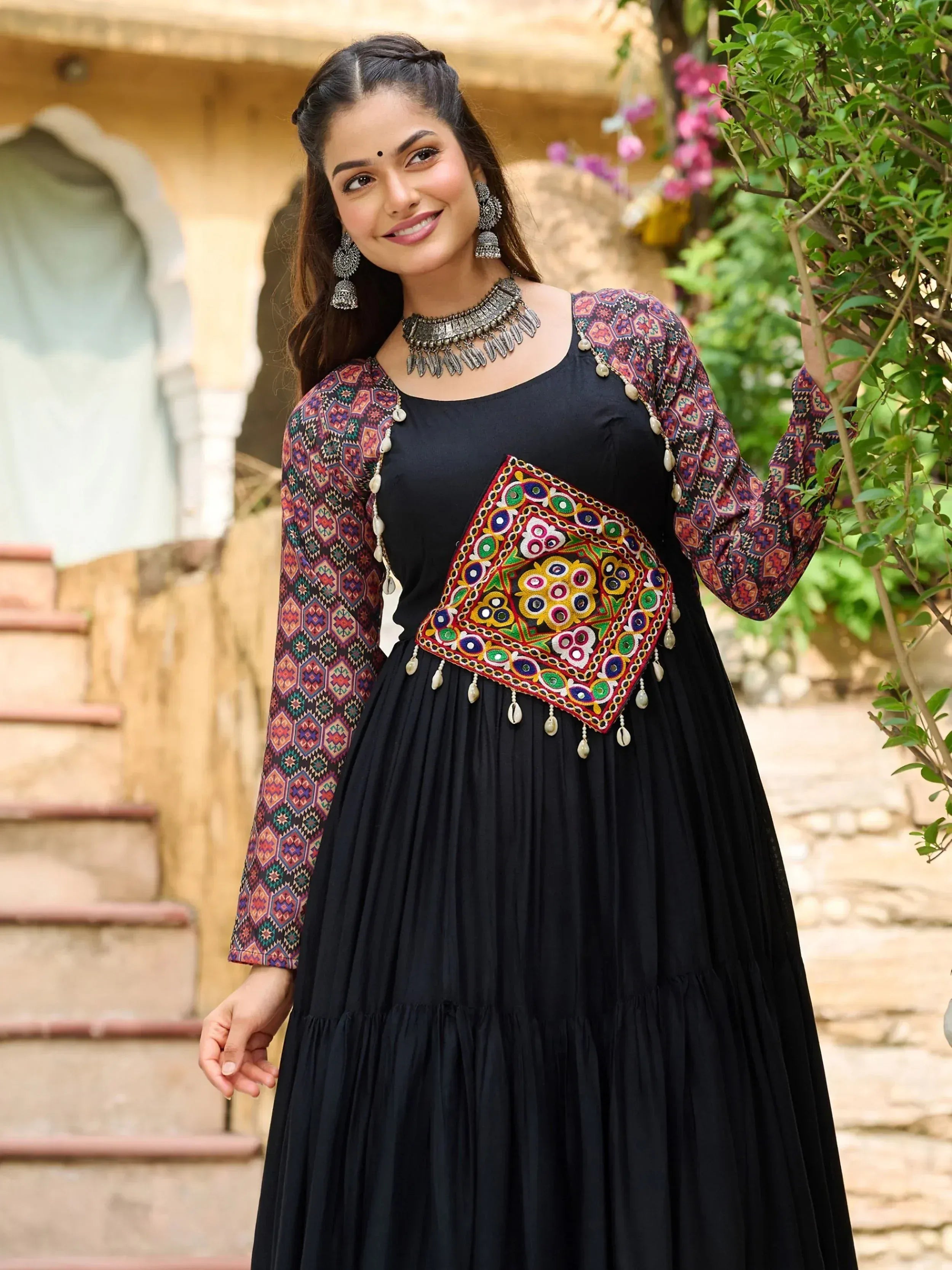 Black ethnic gown with colorful geometric embroidery and mirror work, perfect for Indian festive occasions.