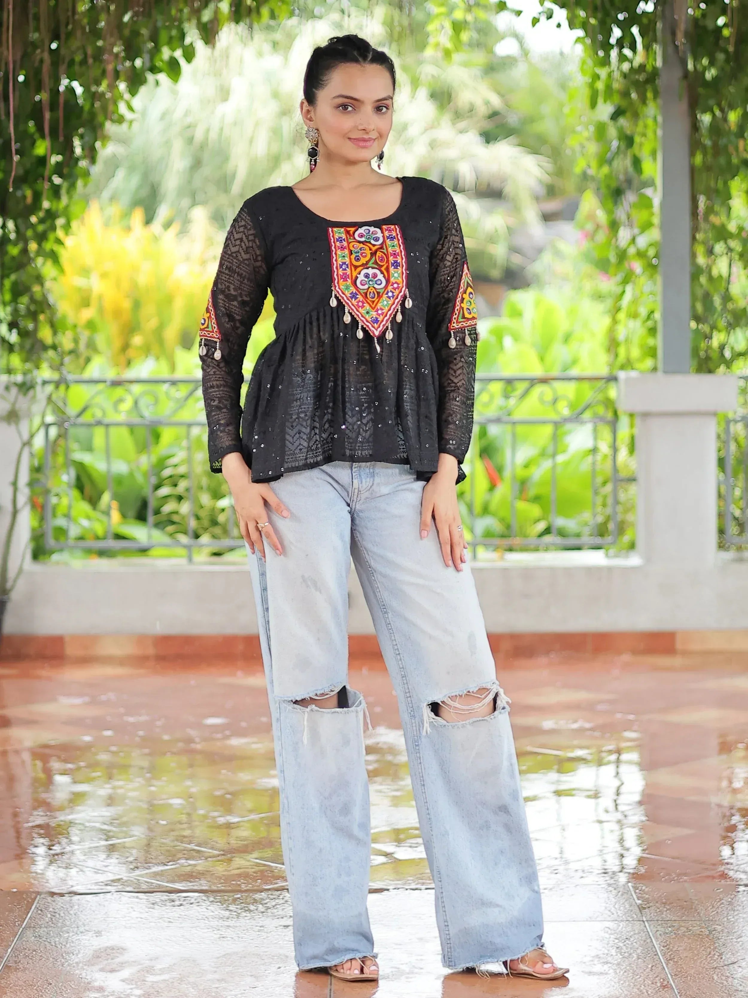 Black embroidered top with colorful patterns paired with ripped jeans, ideal for ethnic fusion fashion.