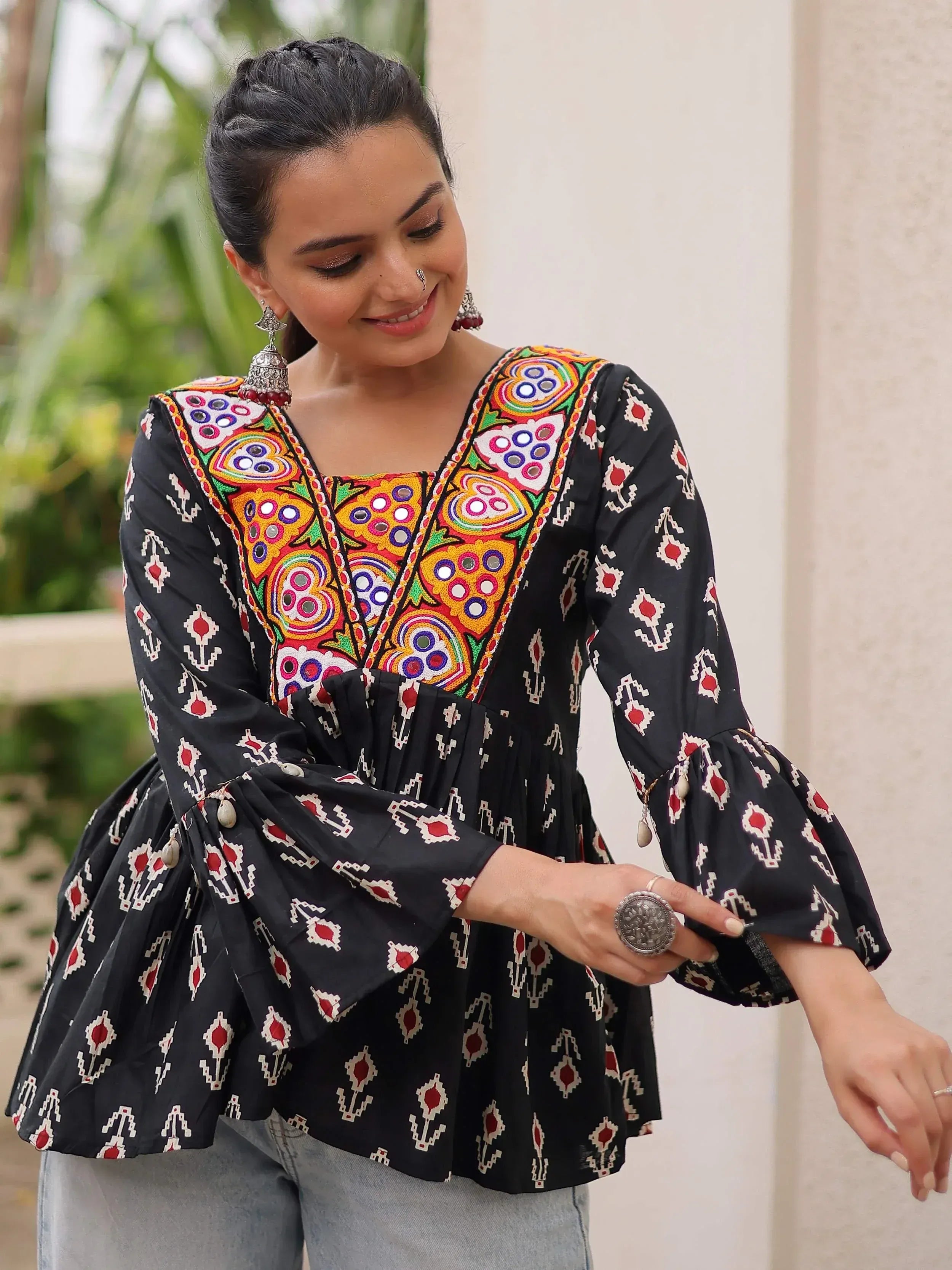 Black ethnic kurti with colorful mirror embroidery and bell sleeves, paired with jeans for casual wear