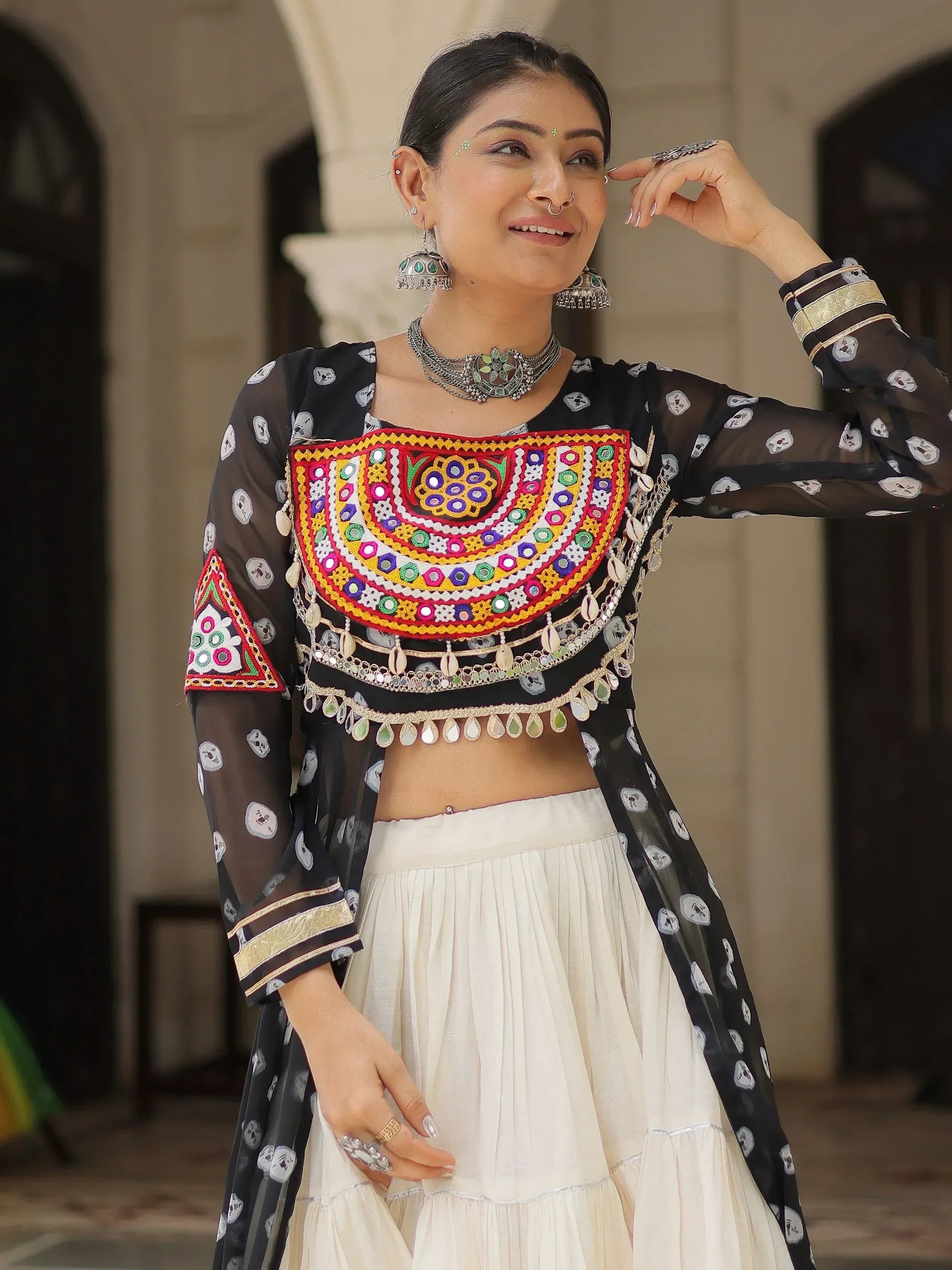 Woman in black sheer embroidered top with mirror work and white lehenga, traditional Indian ethnic wear