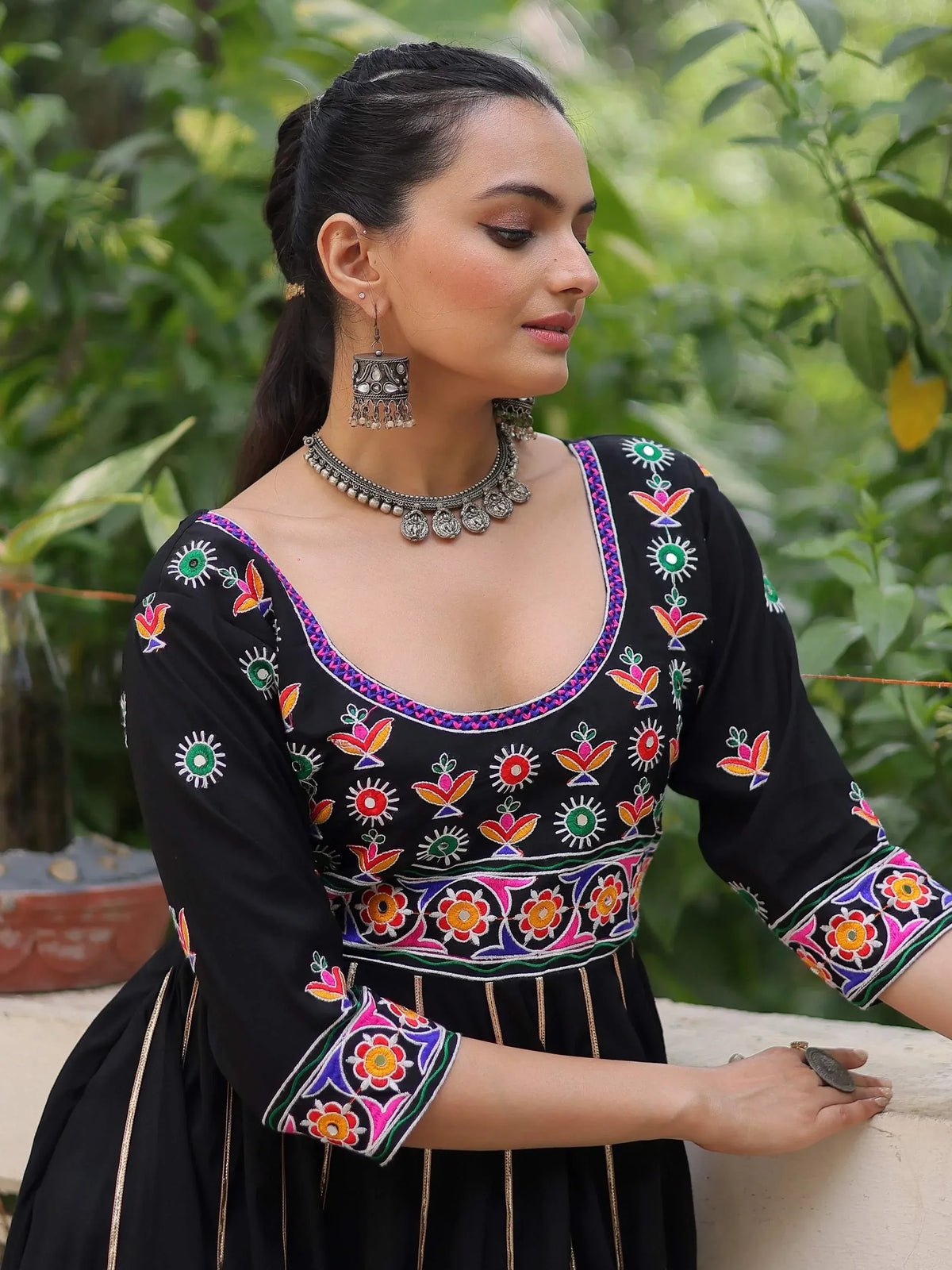 Black embroidered ethnic gown with colorful floral patterns and traditional jewelry