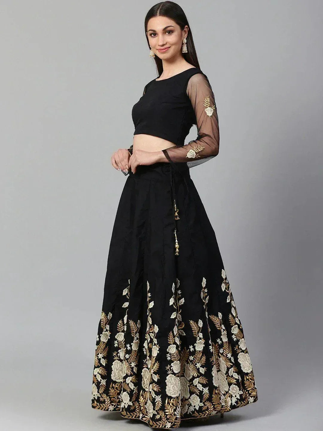 Black lehenga choli with gold floral embroidery, sheer sleeves, and crop top design for ethnic wear