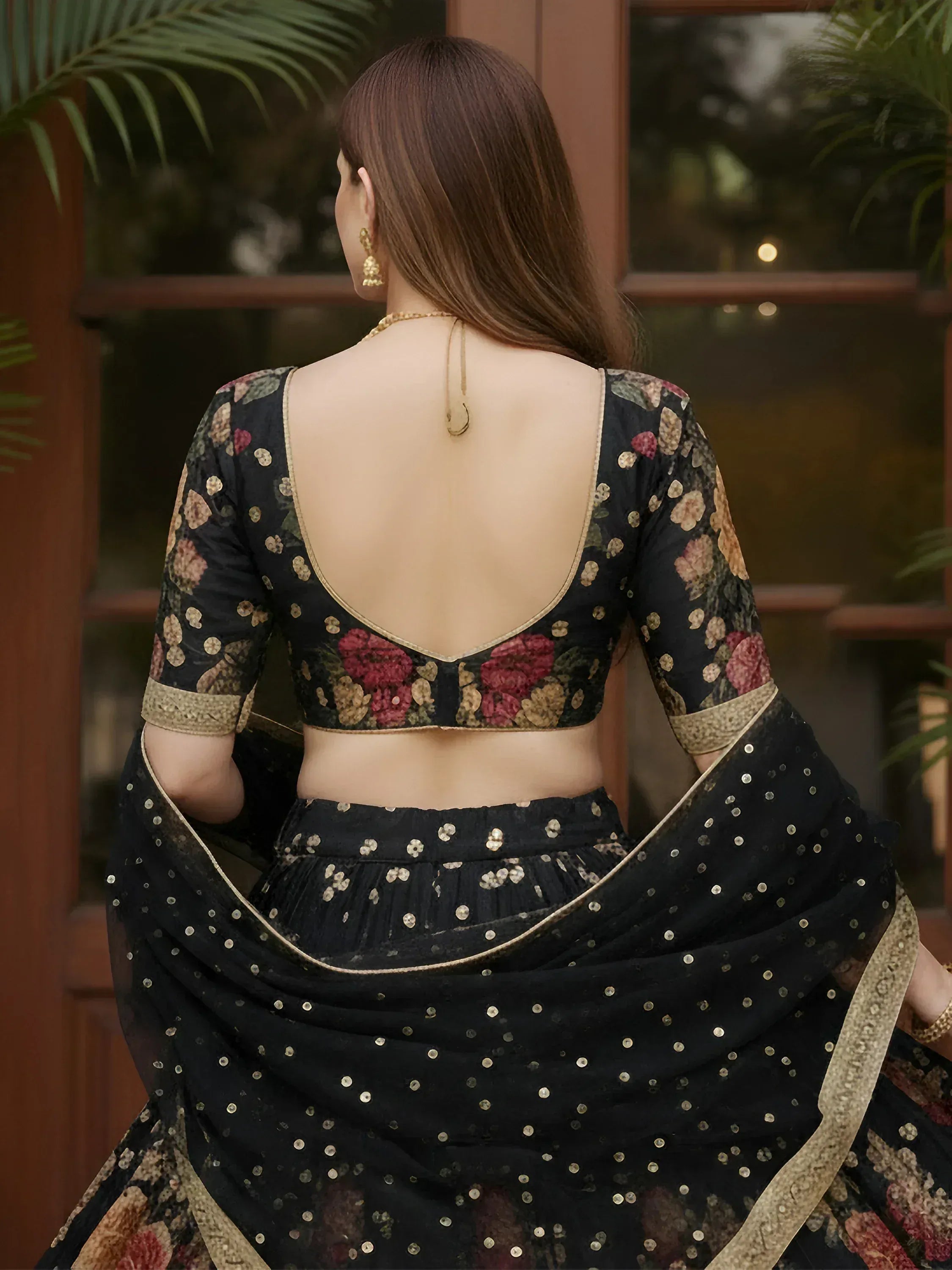 Black floral lehenga choli with gold embroidery and open back, perfect for Indian ethnic wear occasions.