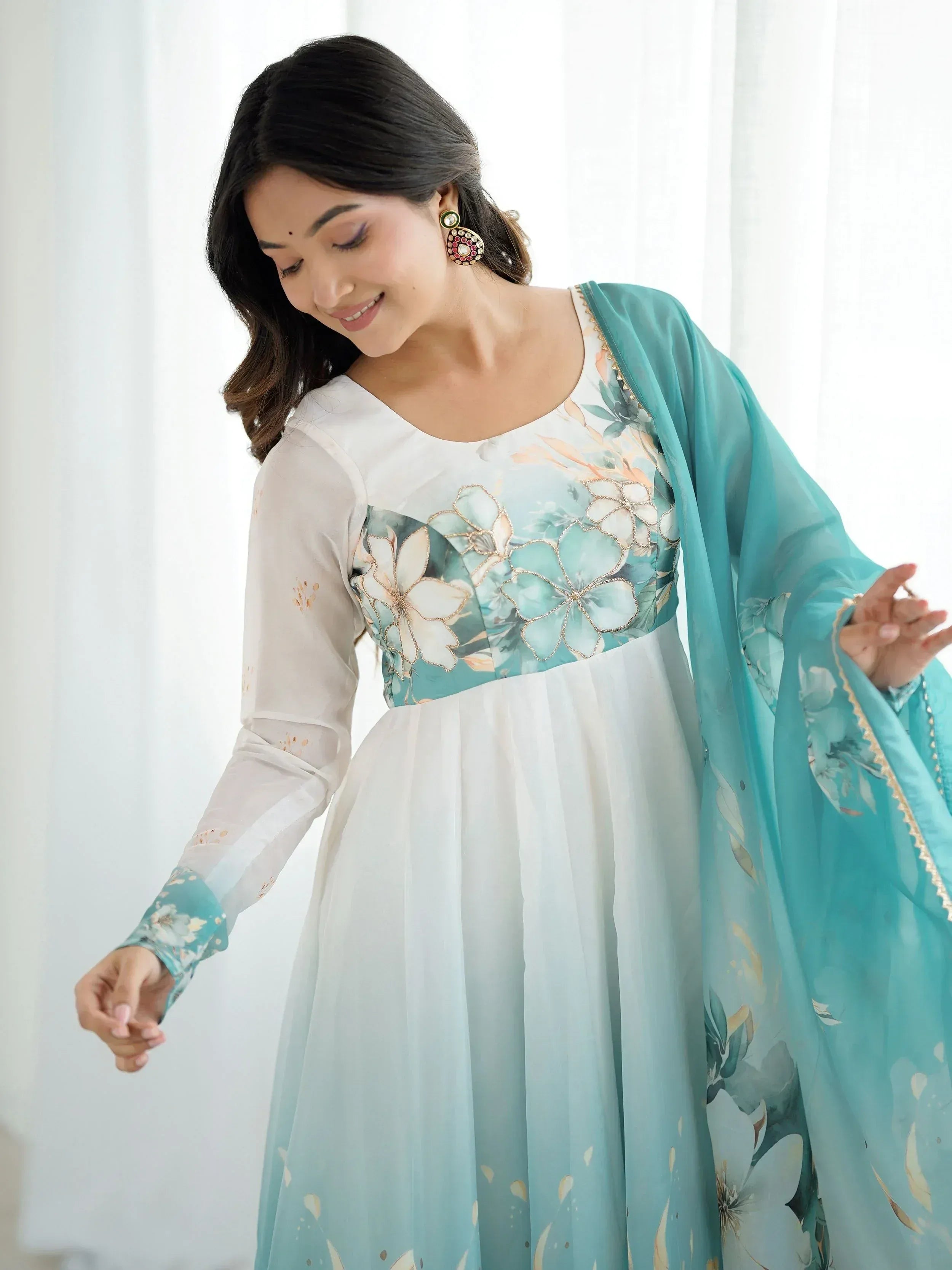 Woman in floral printed ethnic gown with sheer sleeves and matching dupatta, perfect for Indian occasions