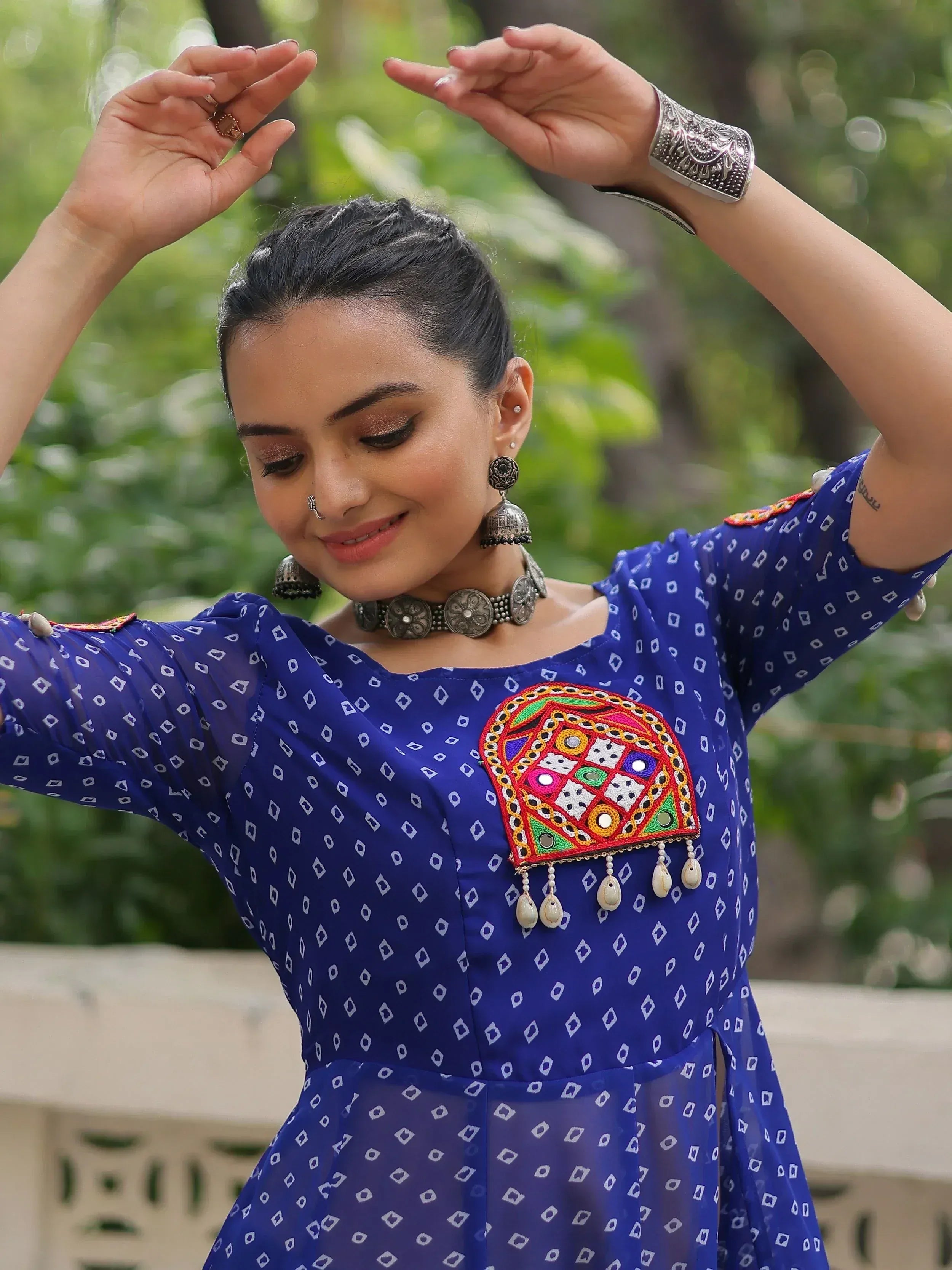 Woman in blue ethnic kurti with mirror work, jhumka earrings, and silver jewelry, posing outdoors