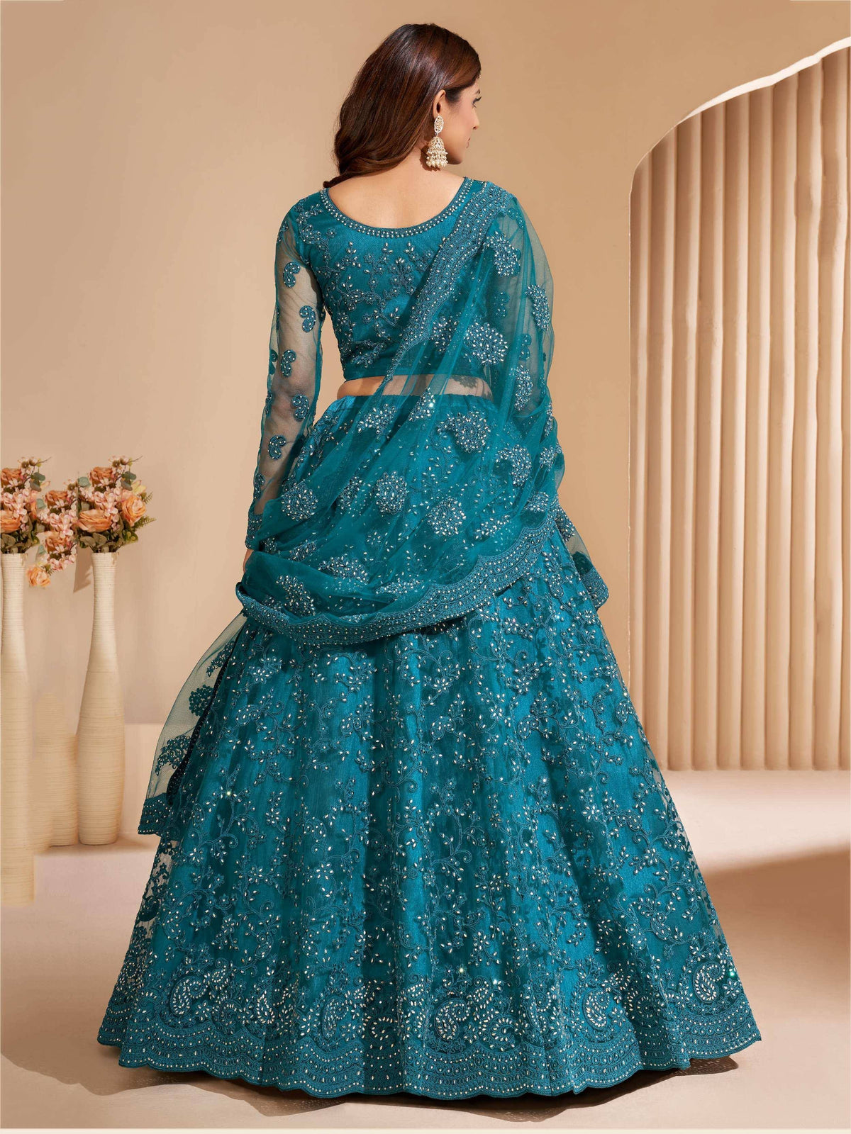 Teal designer lehenga choli with intricate embroidery and sheer dupatta, perfect for Indian ethnic wear occasions.