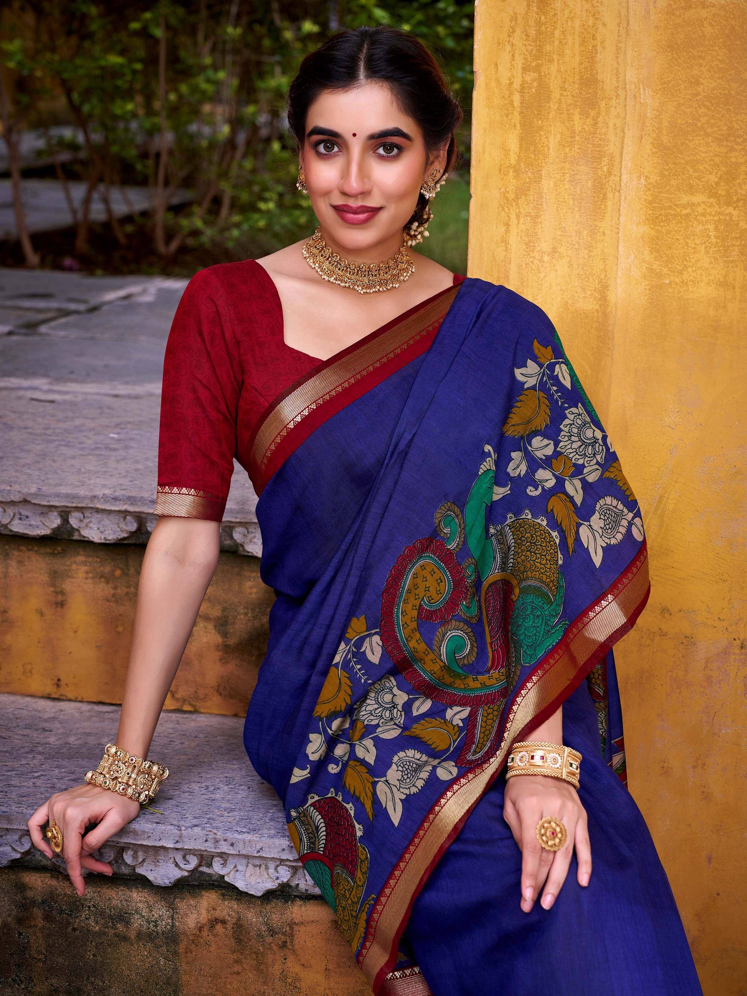 Woman in blue printed saree with red blouse and gold jewelry, ethnic Indian wear