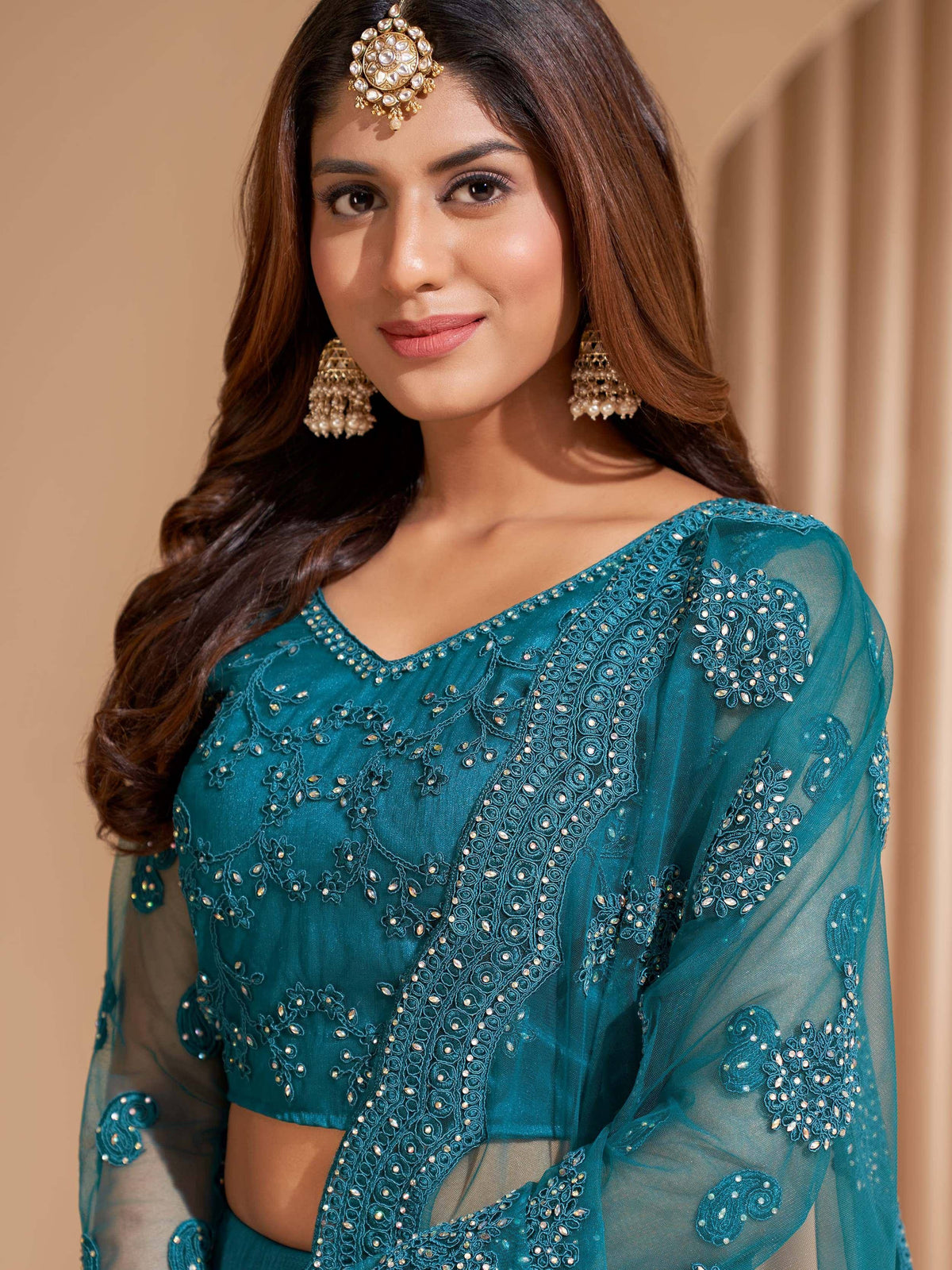 Teal embroidered designer lehenga choli with sheer sleeves and traditional jewelry
