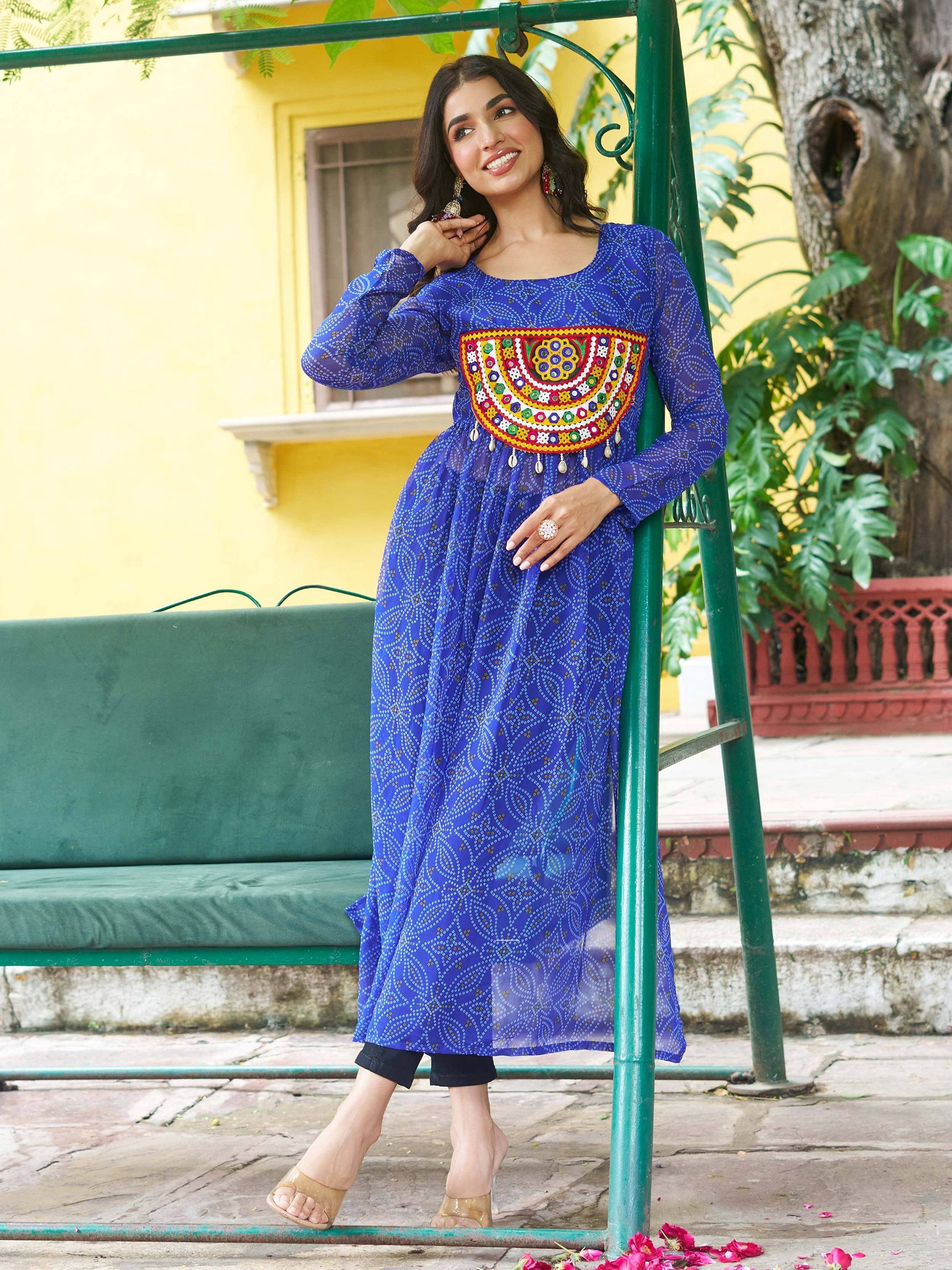 Blue printed ethnic kurti with colorful mirror work, styled with black pants and heels for festive occasions.