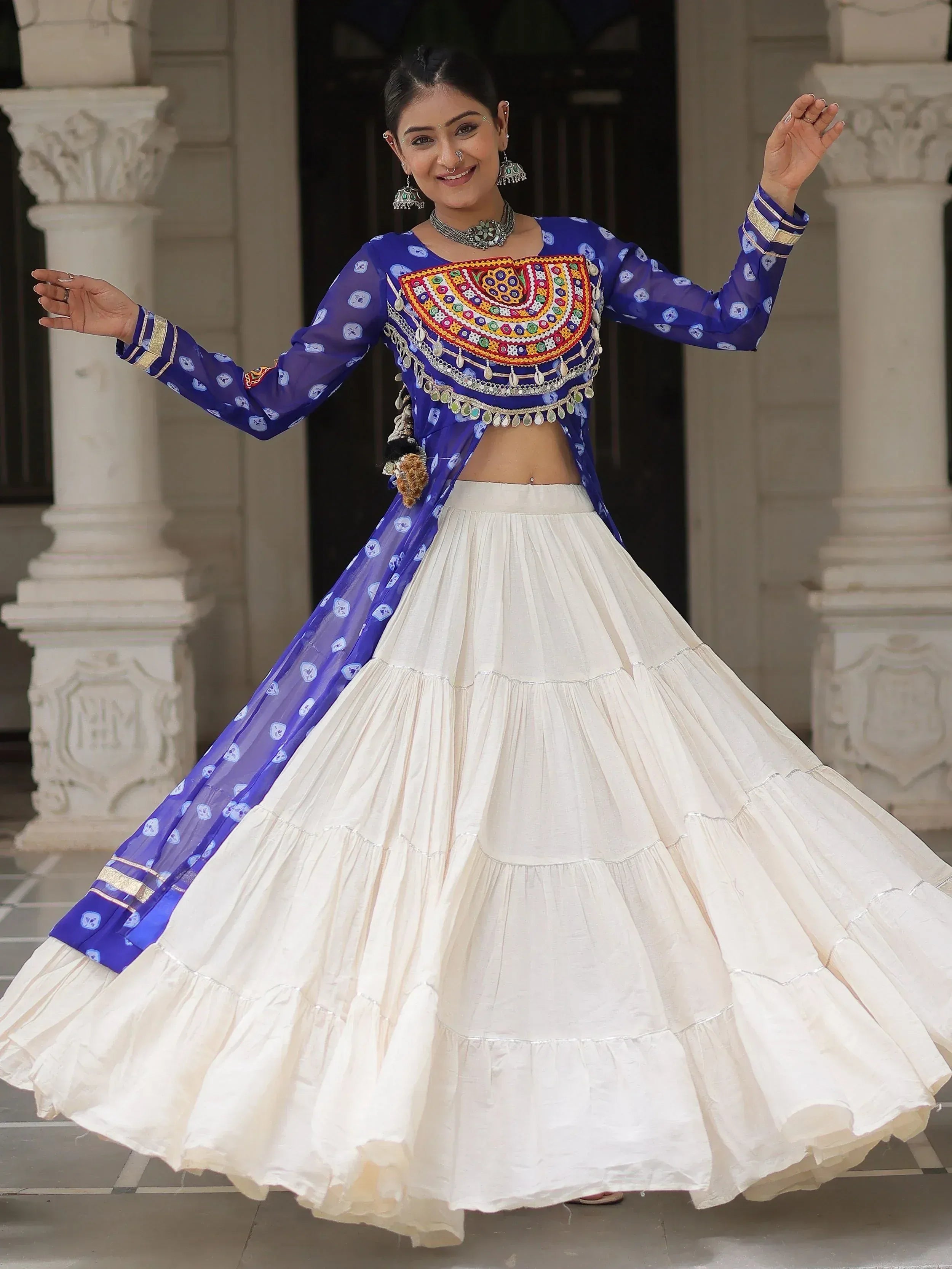 Woman in blue embroidered blouse with white tiered lehenga, traditional Indian ethnic wear