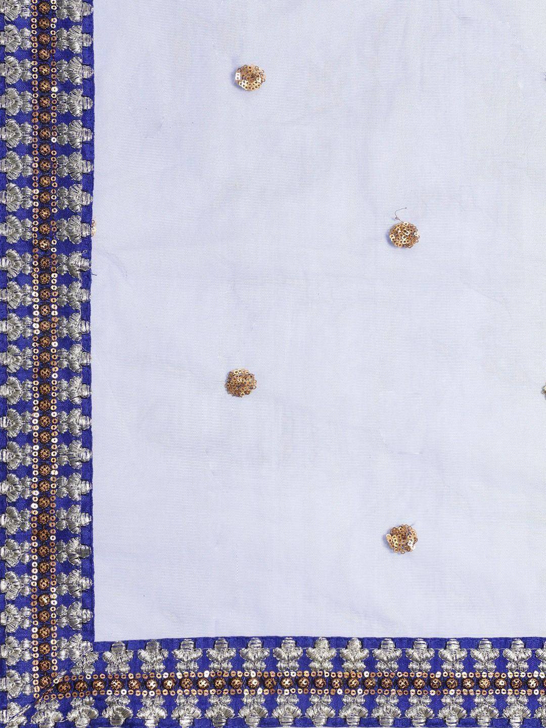 White ethnic wear with blue border, silver-gold embroidery, and sequin embellishments for festive occasions
