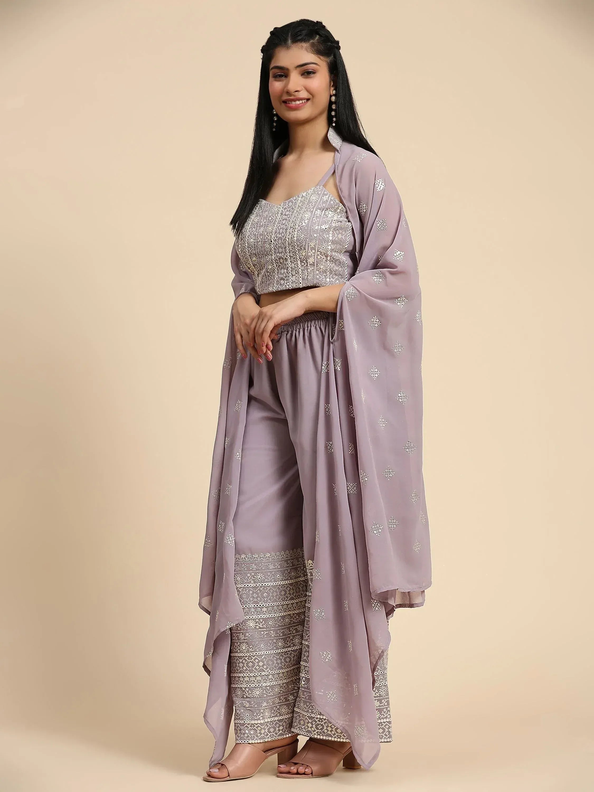 Woman wearing lavender embroidered sharara suit with crop top and dupatta