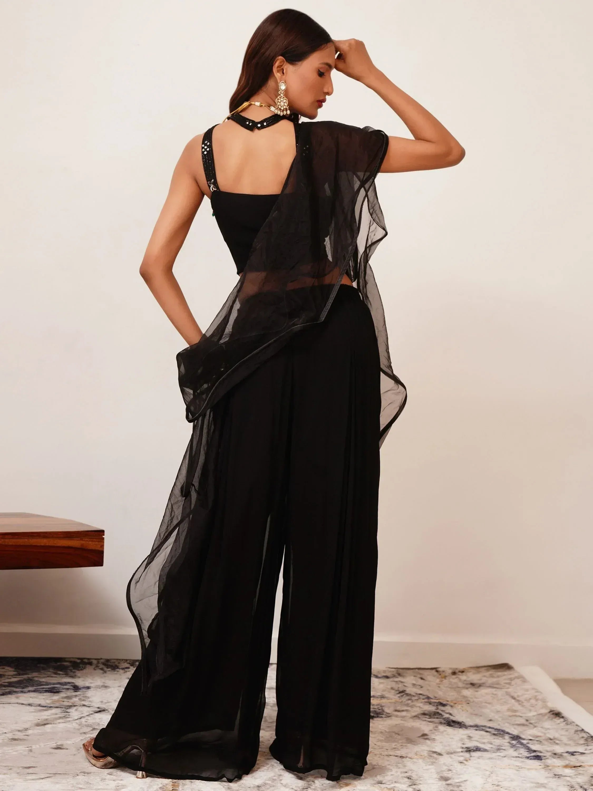 Woman wearing modern black ethnic palazzo suit with sheer dupatta and embellished blouse