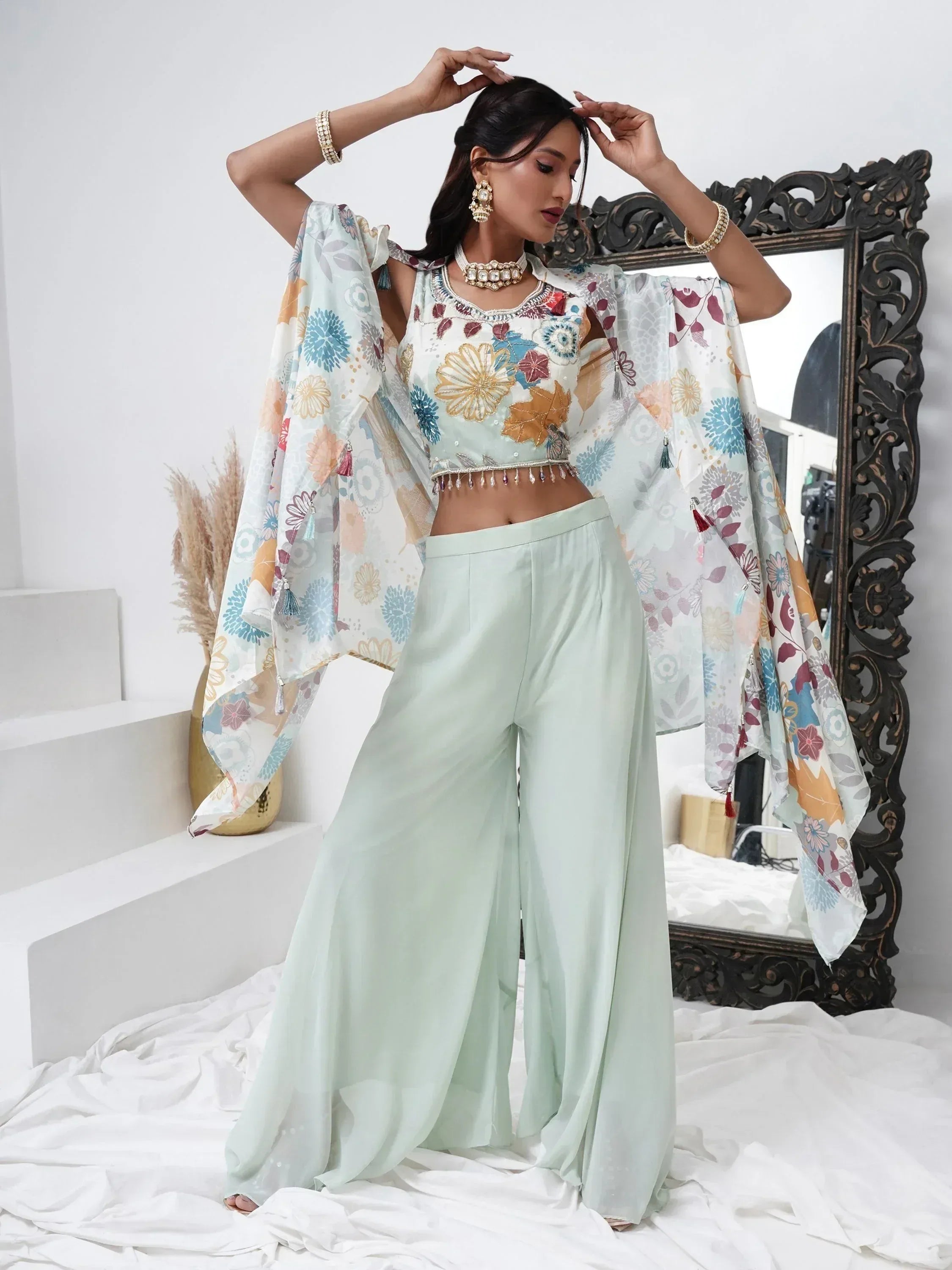 Woman wearing pastel floral embroidered crop top with wide-leg palazzo pants and dupatta, styled with ethnic jewelry