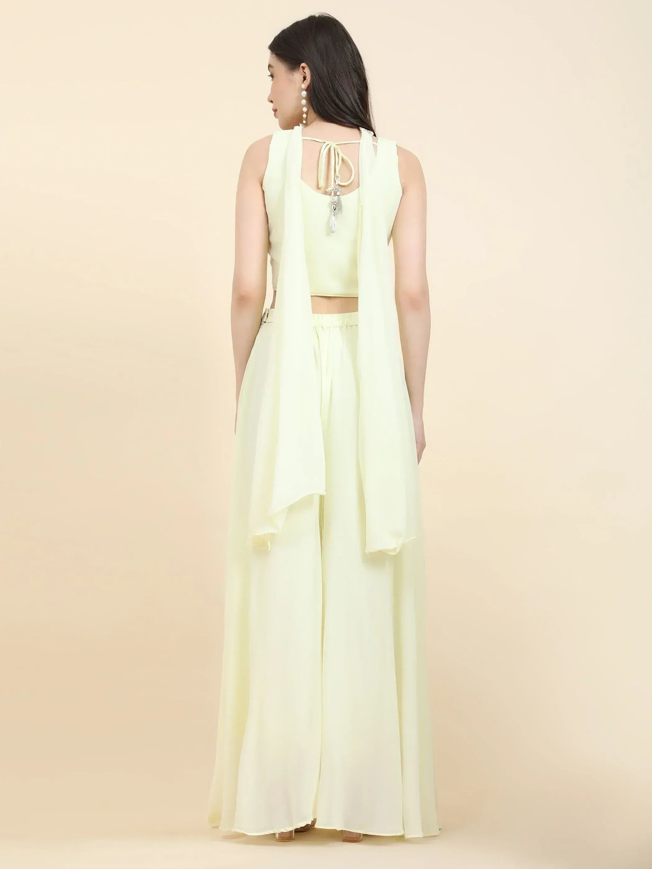 Woman in pale yellow lehenga choli set with dupatta, seen from the back