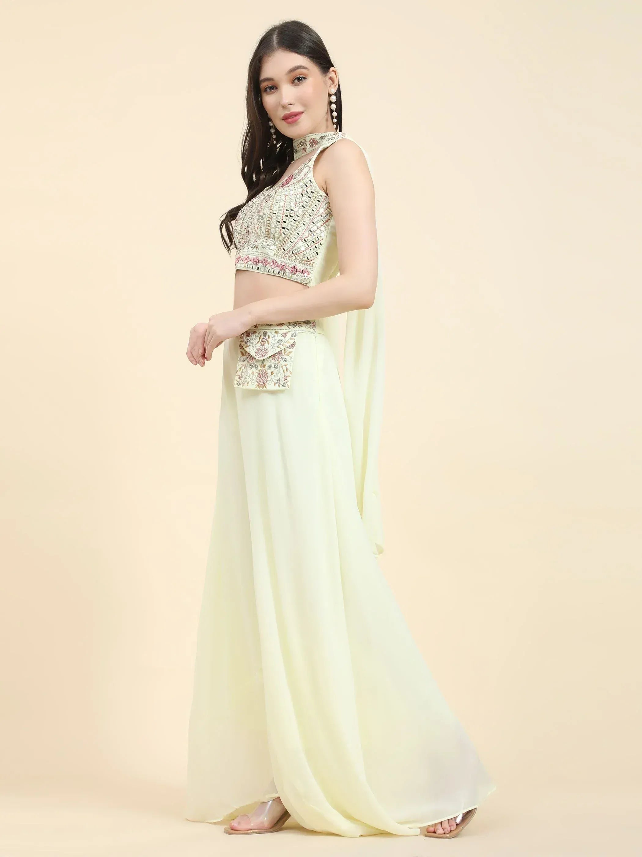 Woman in pastel yellow lehenga choli with mirror work and embroidered details