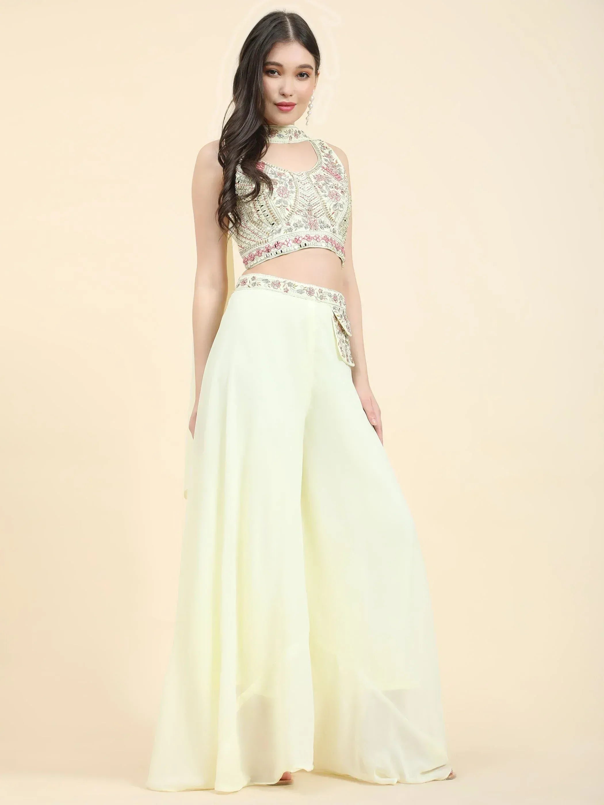 Woman wearing a light yellow embroidered crop top and wide leg palazzo pants, ethnic outfit