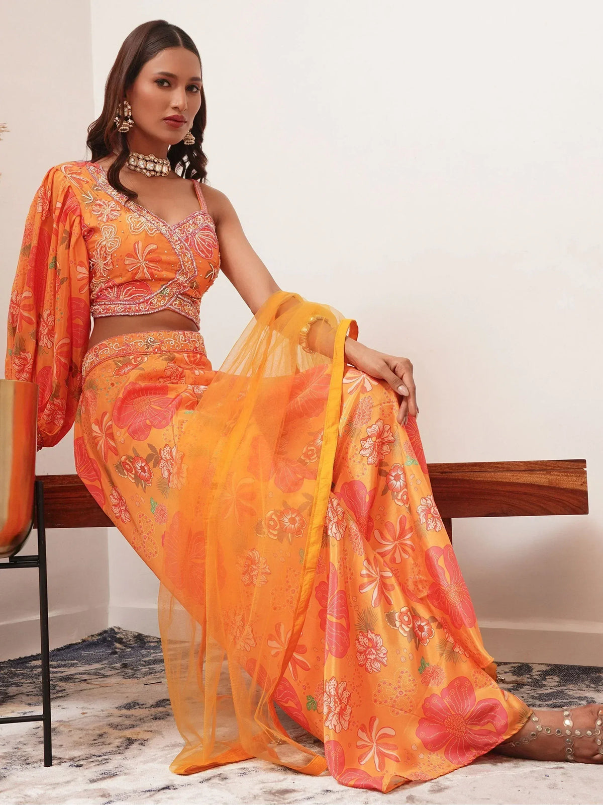 Vibrant orange floral print lehenga choli with sheer dupatta, perfect for Indian ethnic wear occasions.