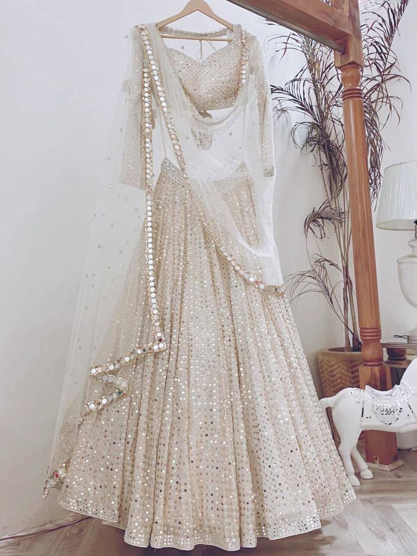 Elegant ivory mirror-work lehenga choli with sheer dupatta, perfect for Indian weddings and festive occasions.