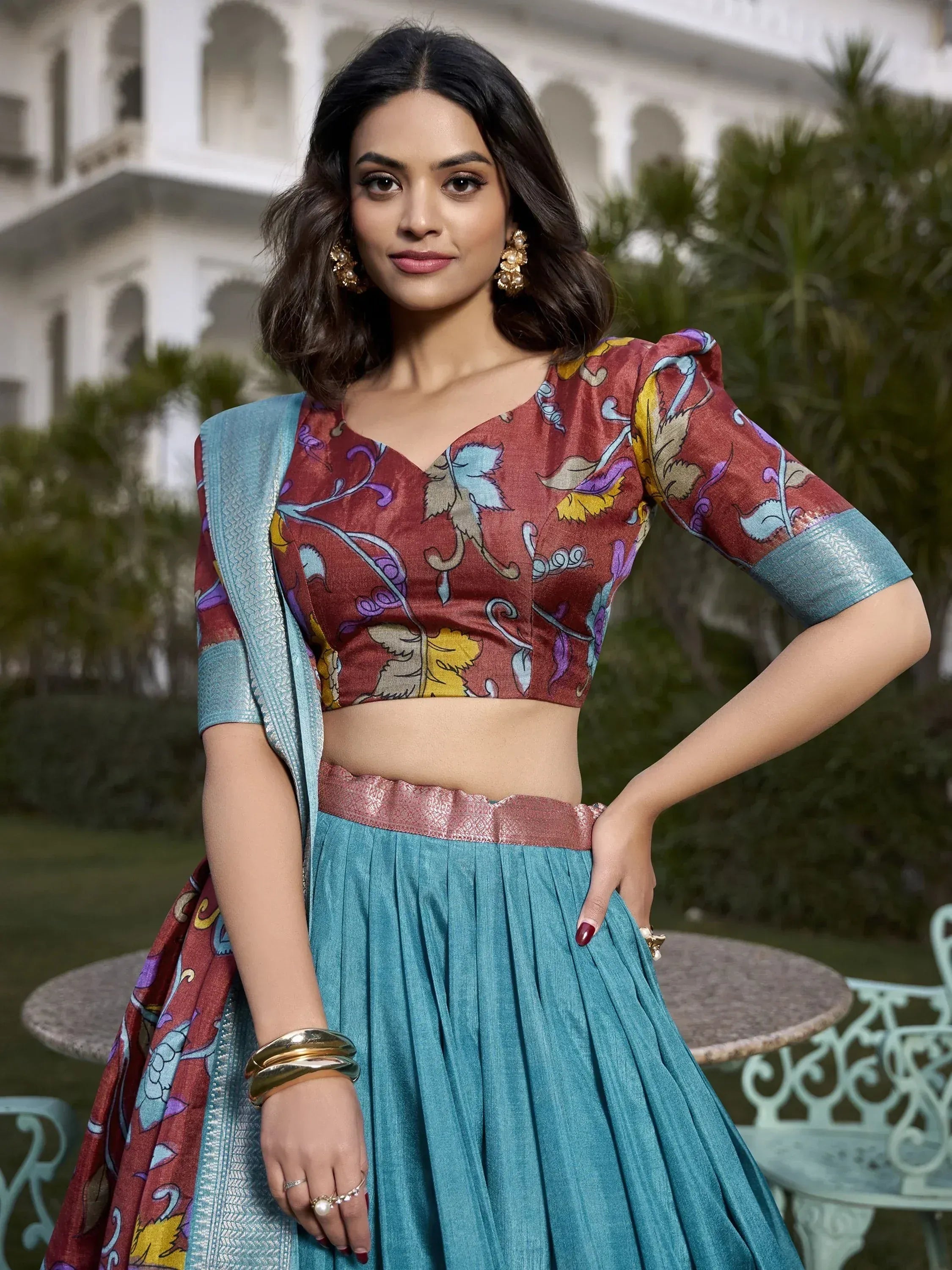 Woman in designer lehenga choli with floral blouse and teal skirt, ethnic Indian wear